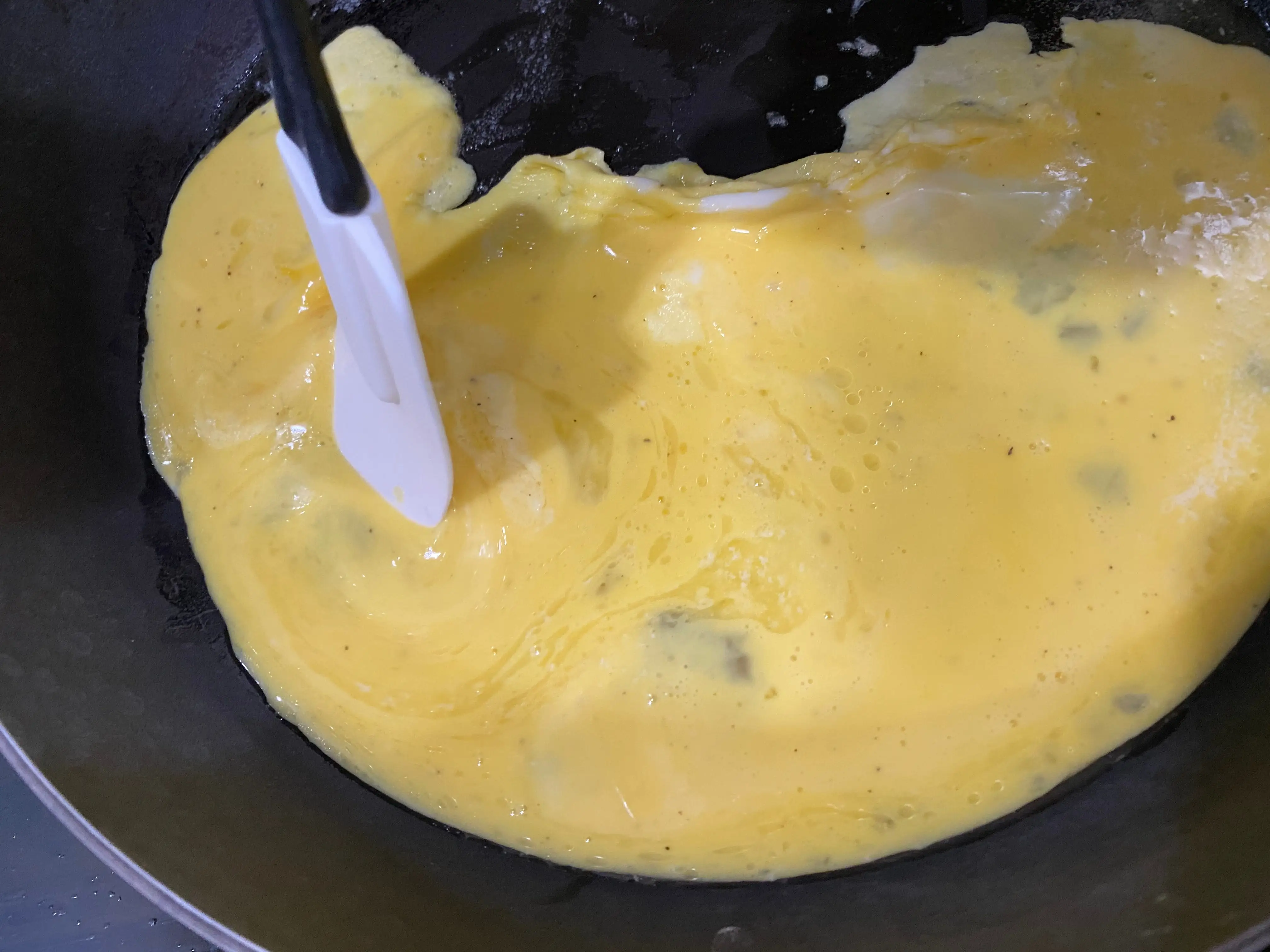 Spatula pushing egg mixture in pan