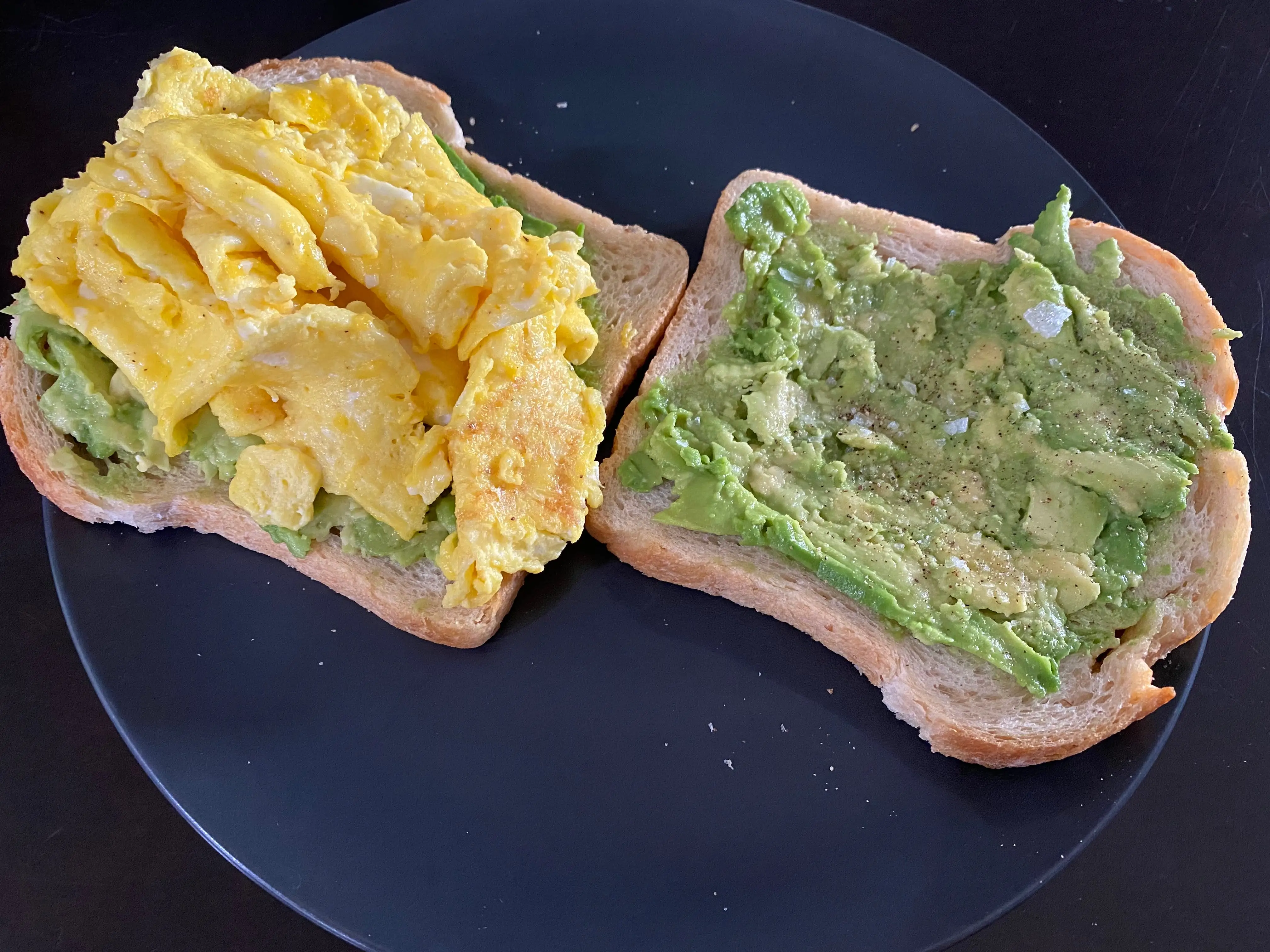 Folded egg on avocado toast next to piece of plain avocado toast