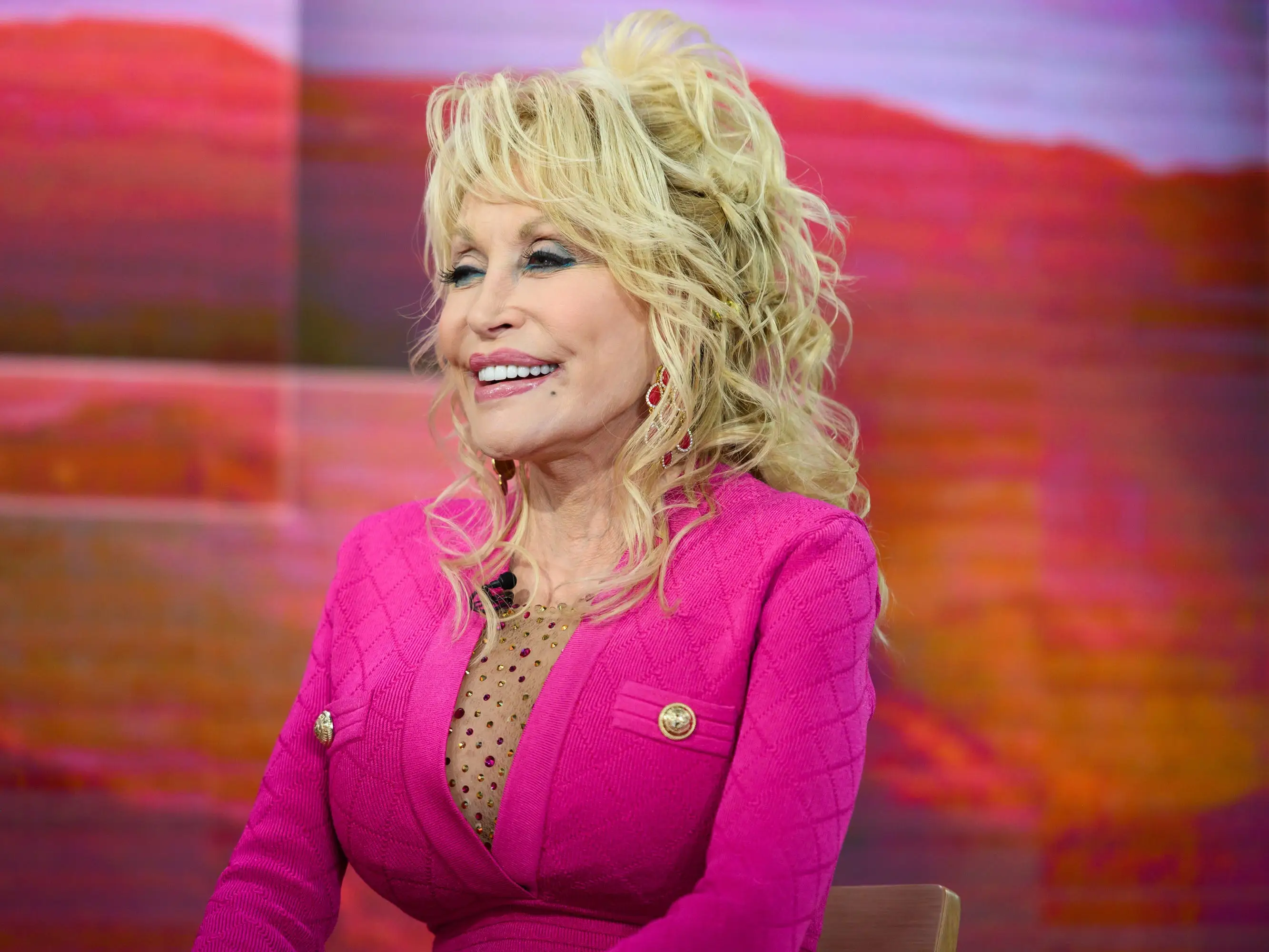 Dolly Parton smiles, facing away from the camera.