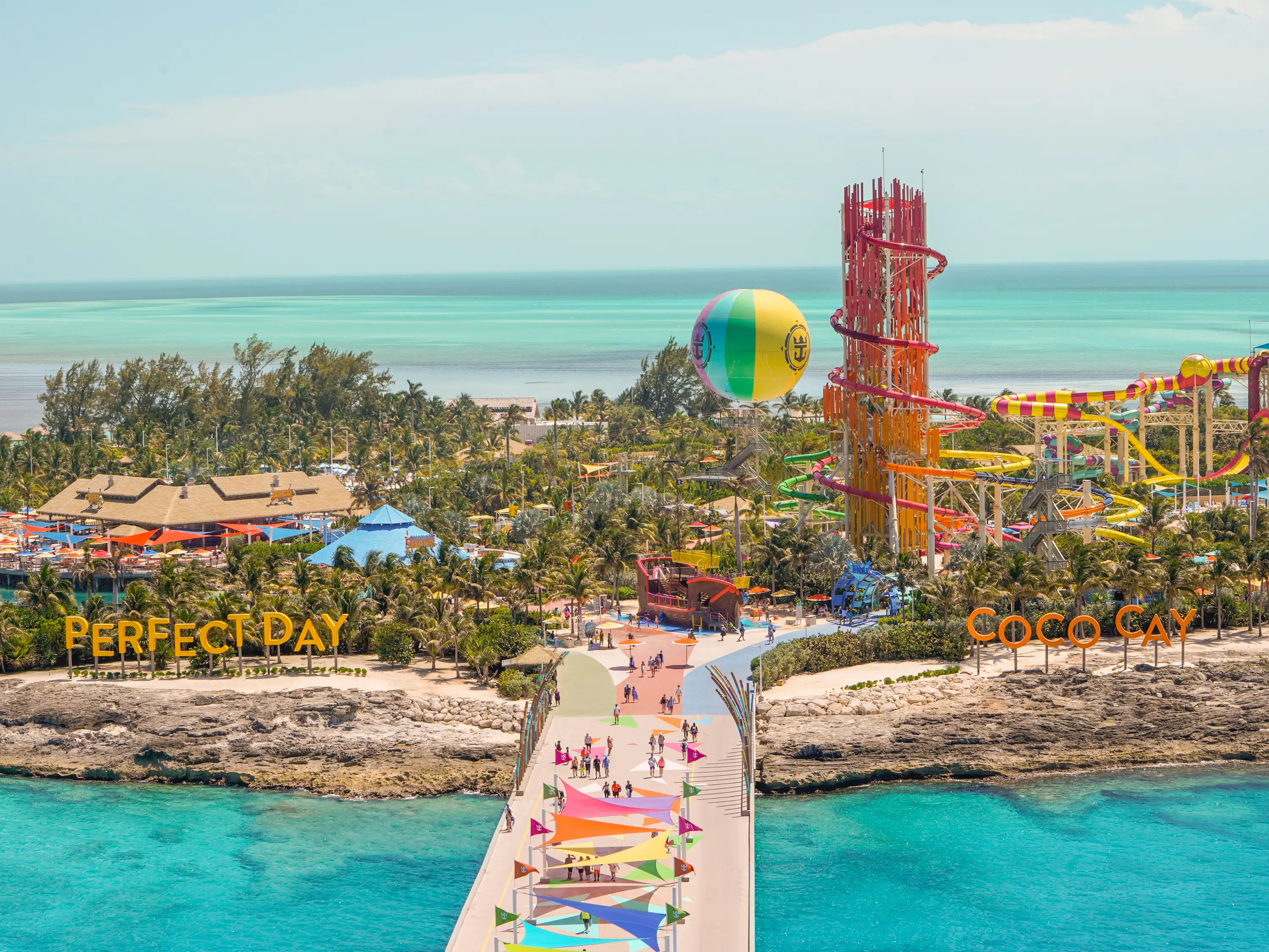 Perfect Day at CocoCay island with hot air balloon and water slides seen from above with clear blue waters surrounding it and partly cloudy skies behind