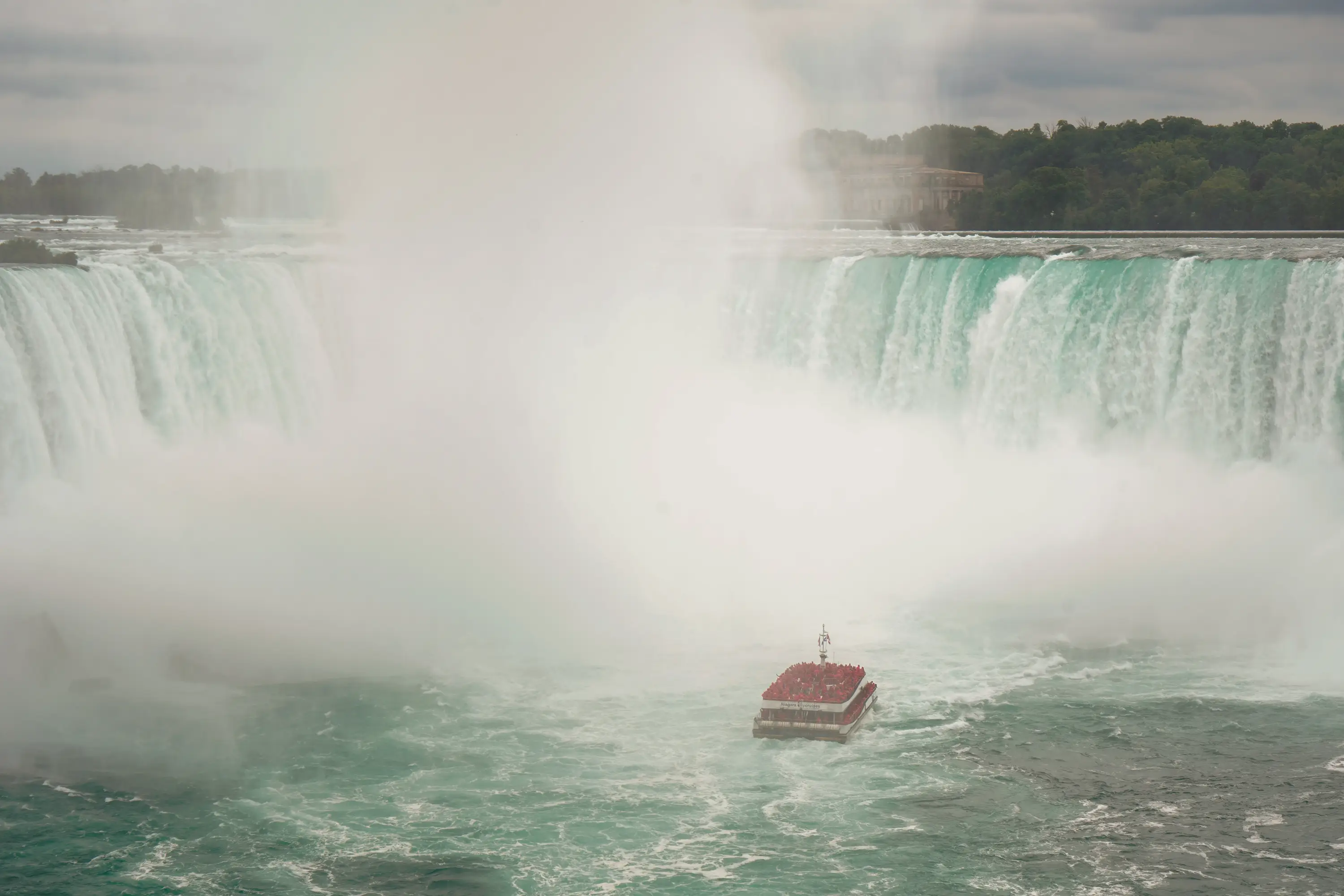 A boat approaches Horseshoe Falls at Niagara Falls on a cloudy day