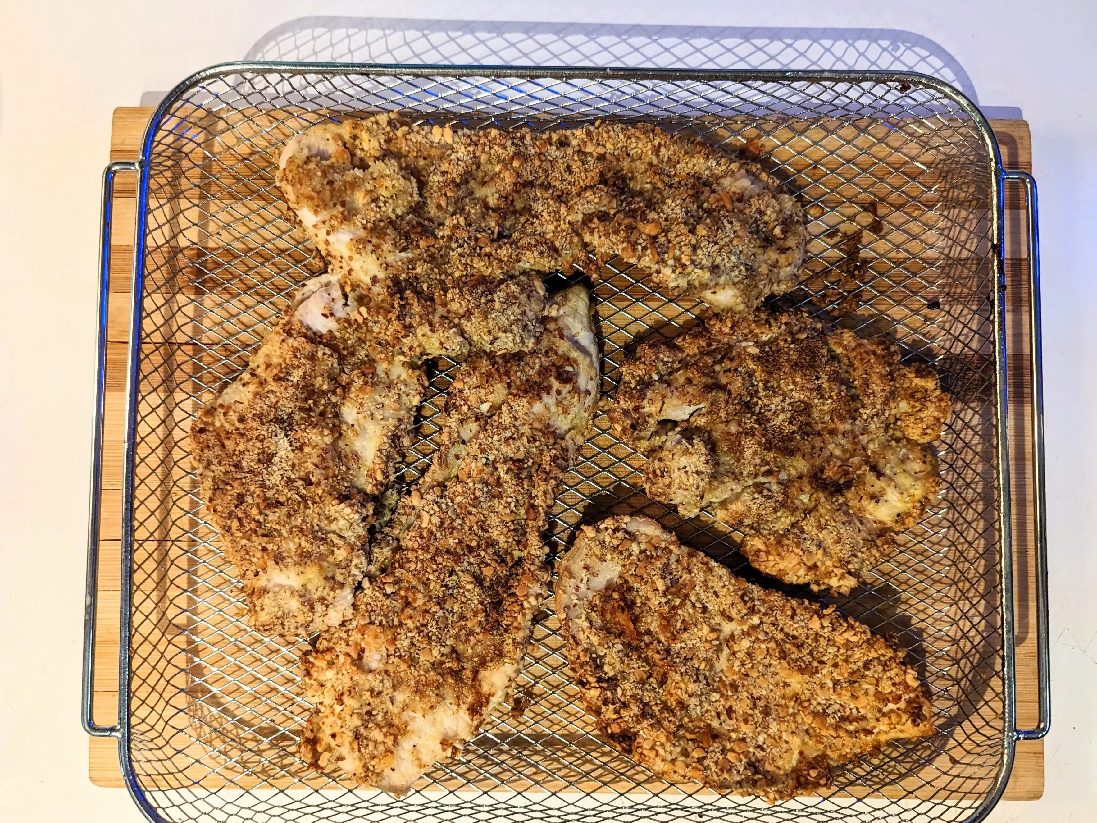 pieces of nut crusted chicken sitting in an air-fryer basket