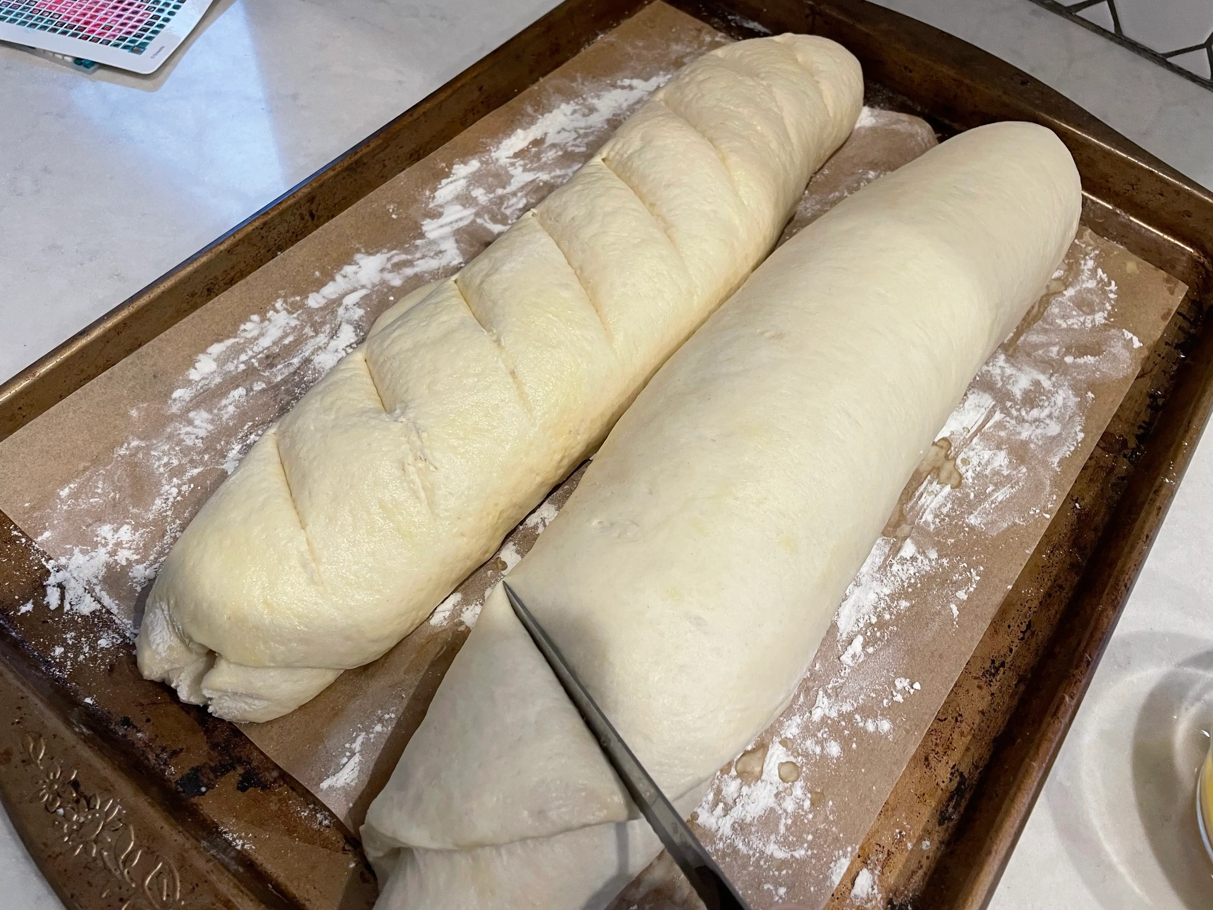 knife cutting into a risen baguette dough