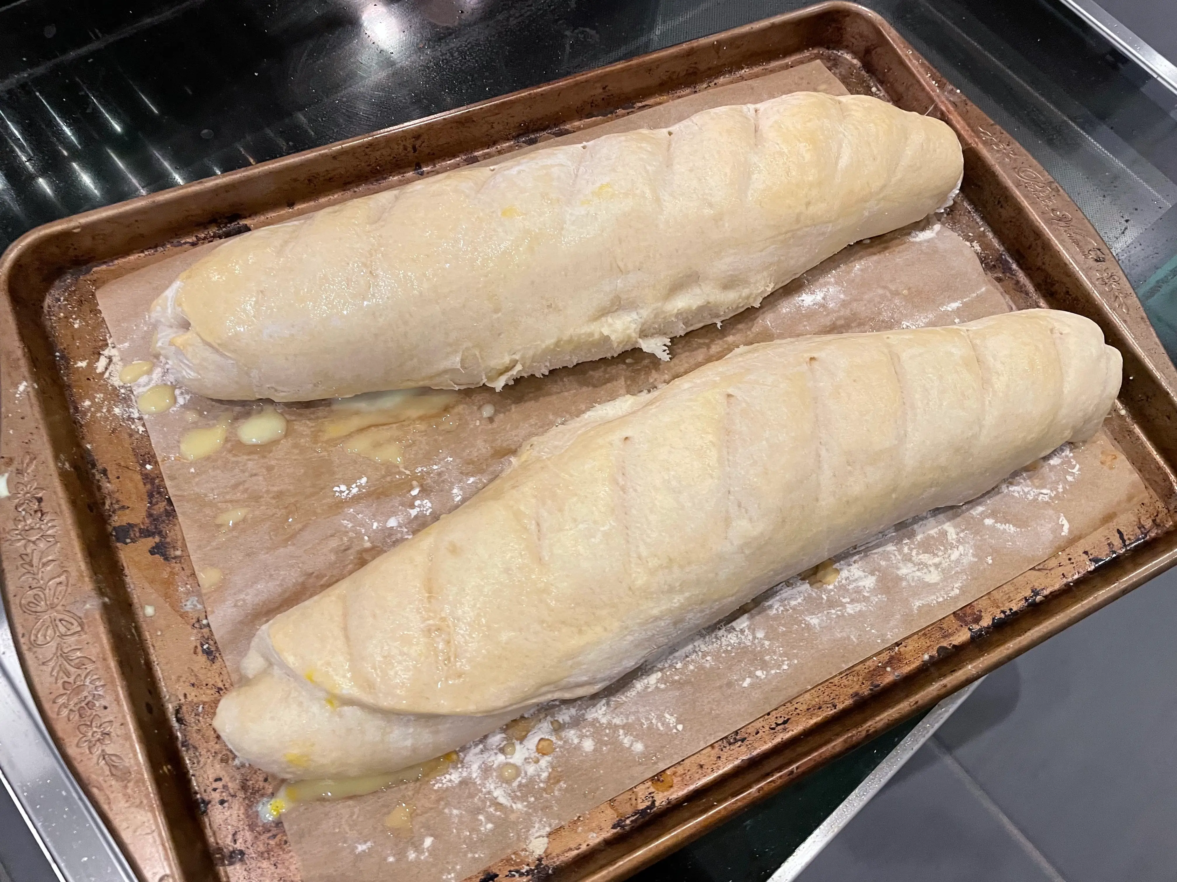 two partially cooked baguettes on a cookie sheet