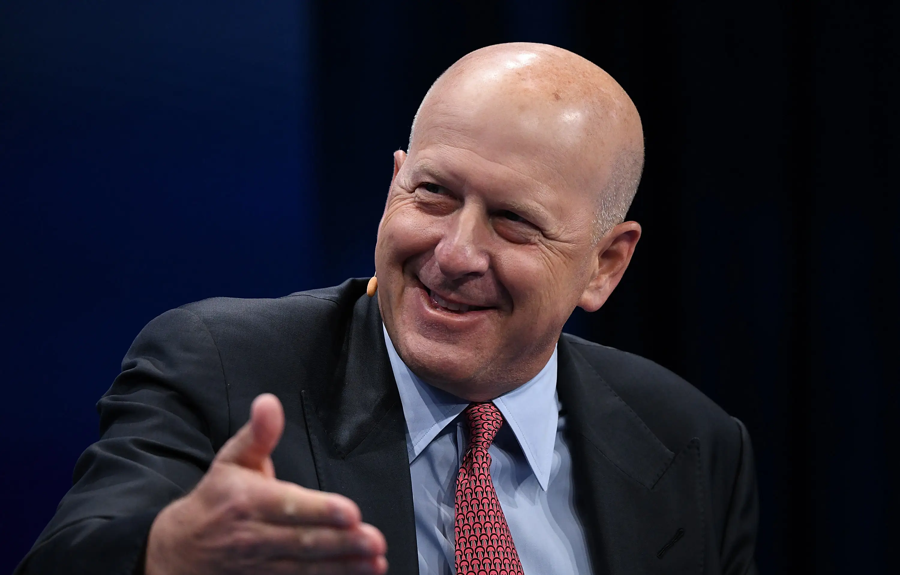 A bald man in a suit smiles
