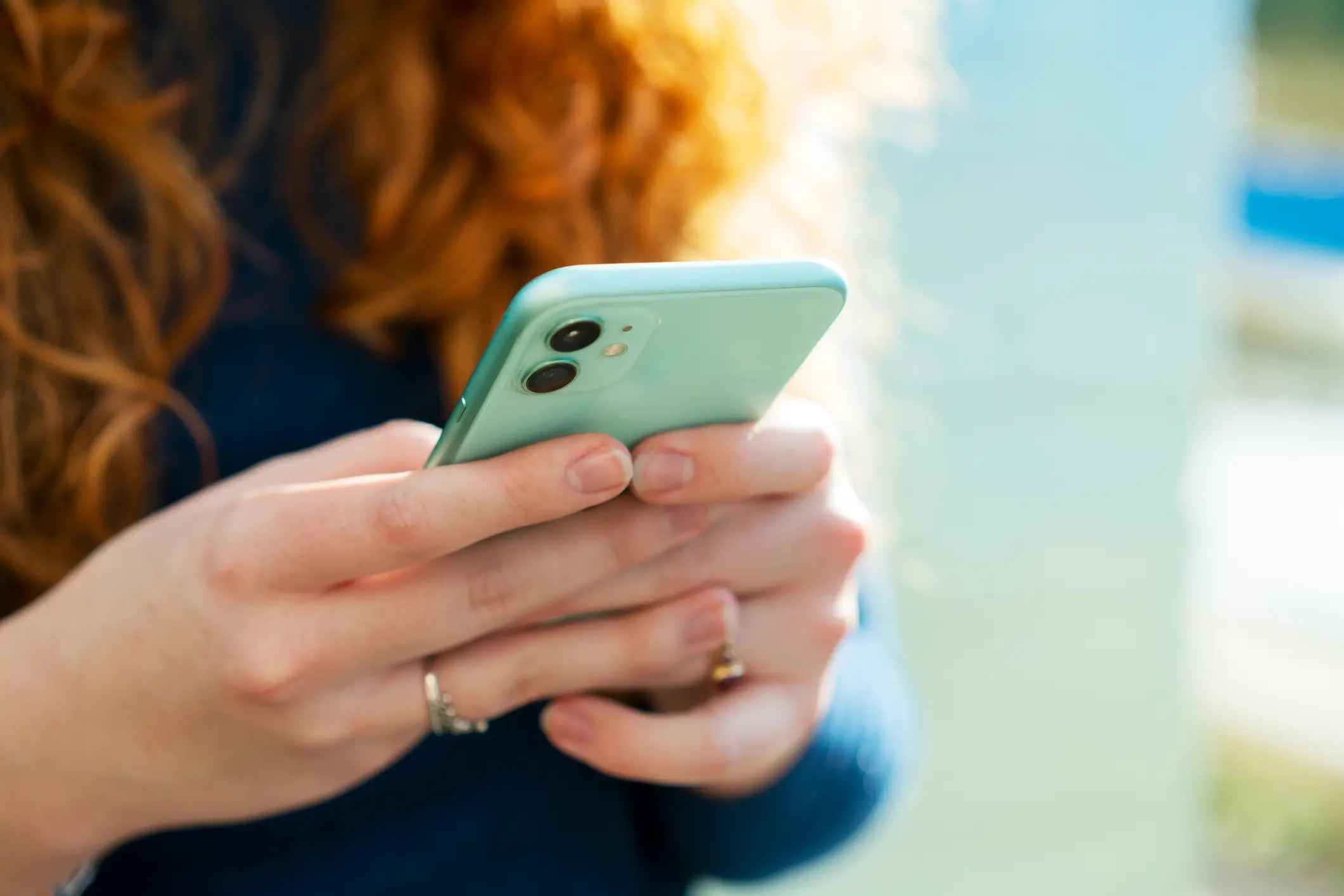 A close-up of a person's hands holding and typing on a phone