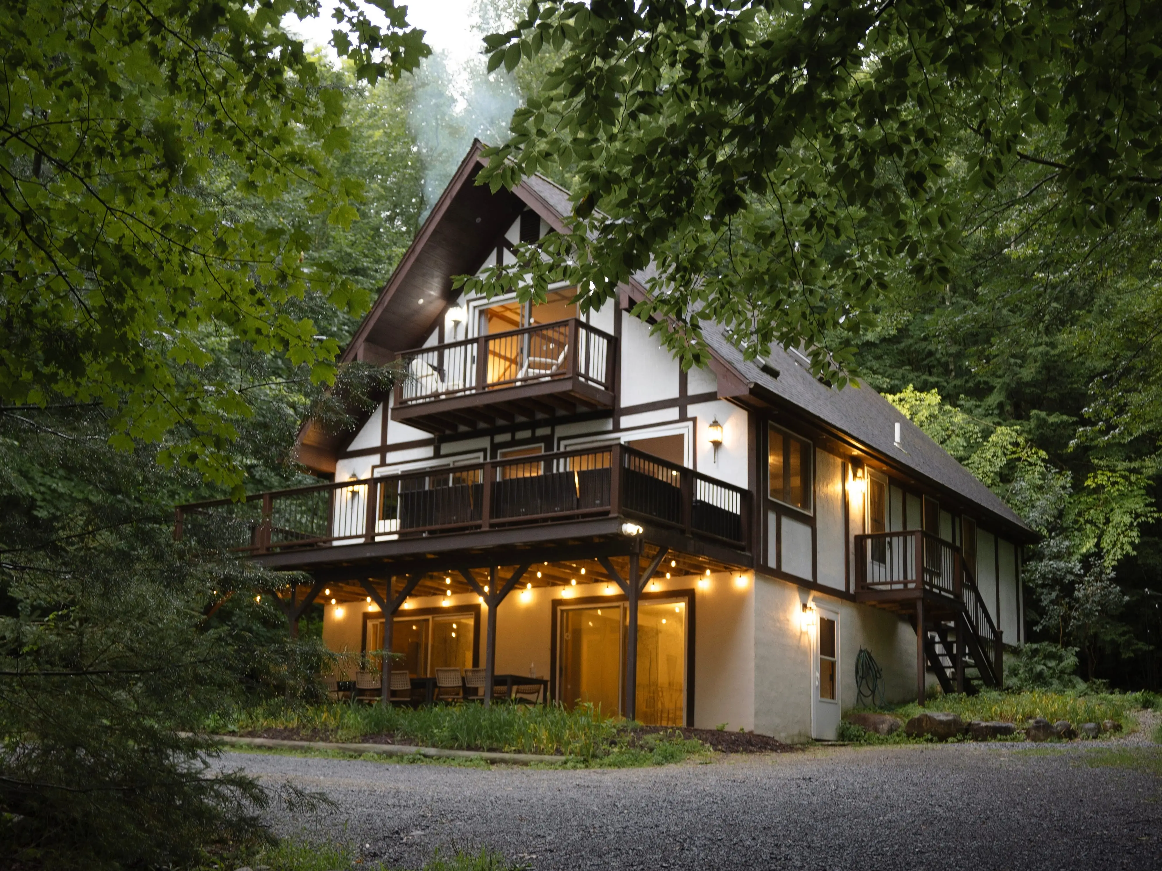A three-story house in the woods with warm lights.