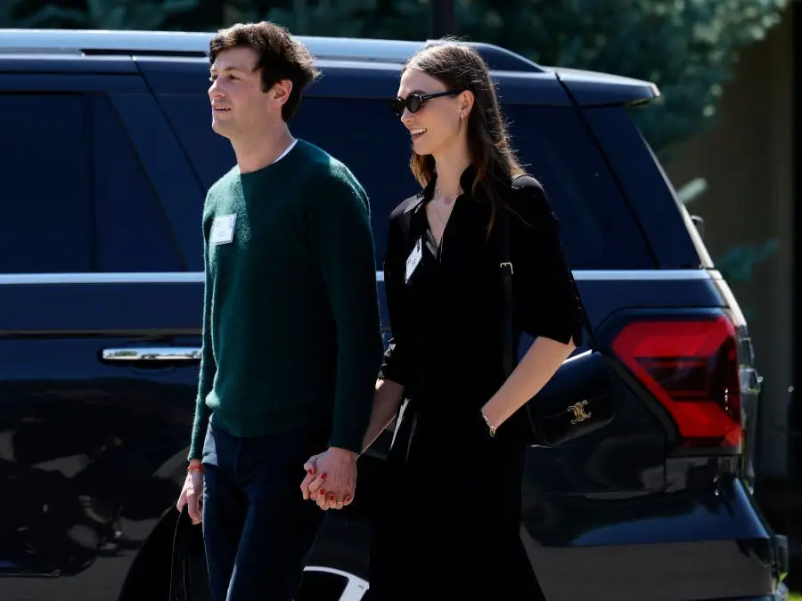 Josh Kushner and Karlie Kloss hold hands while exiting a car.