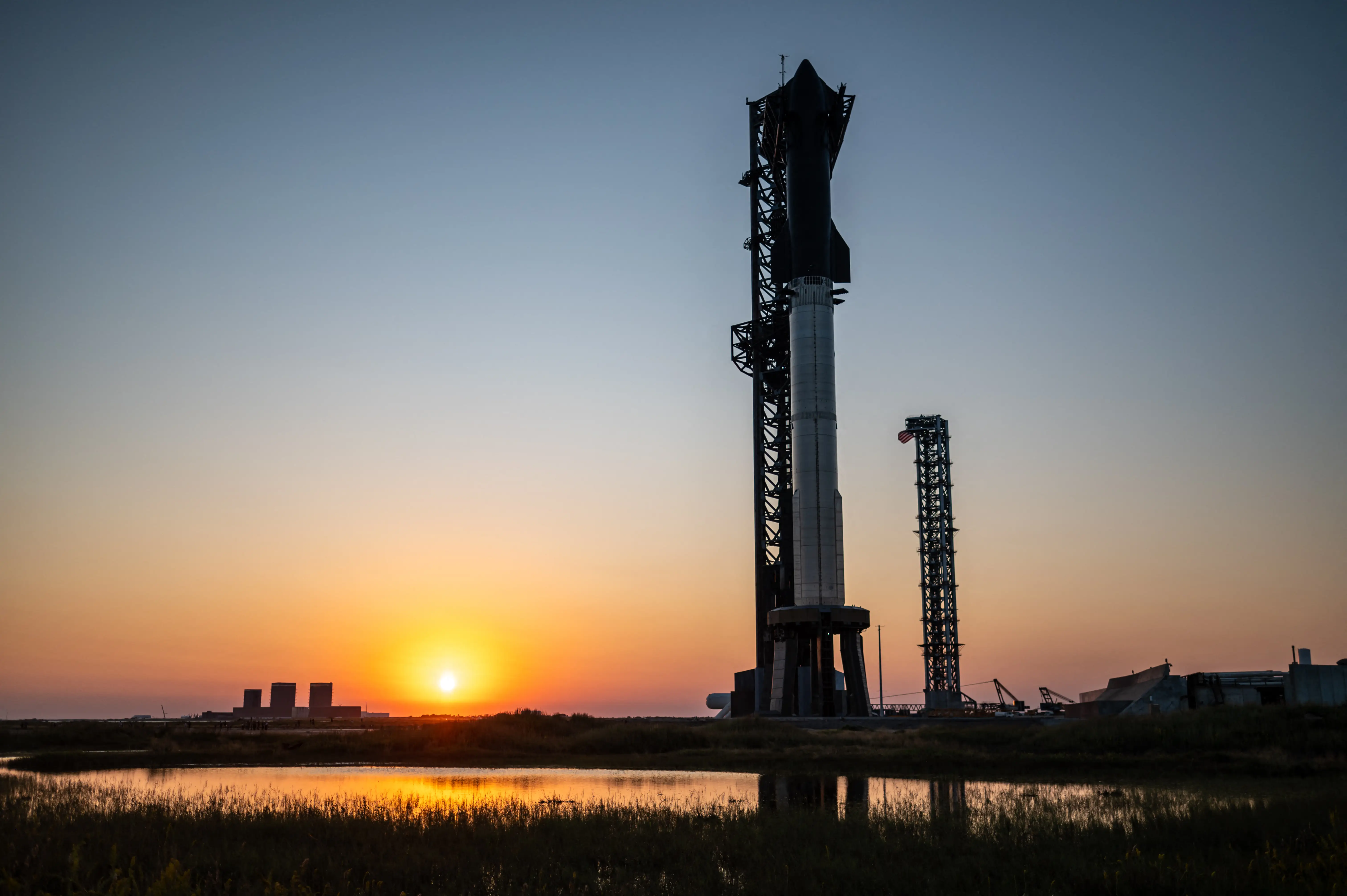 SpaceX Starship with the sun setting behind it.