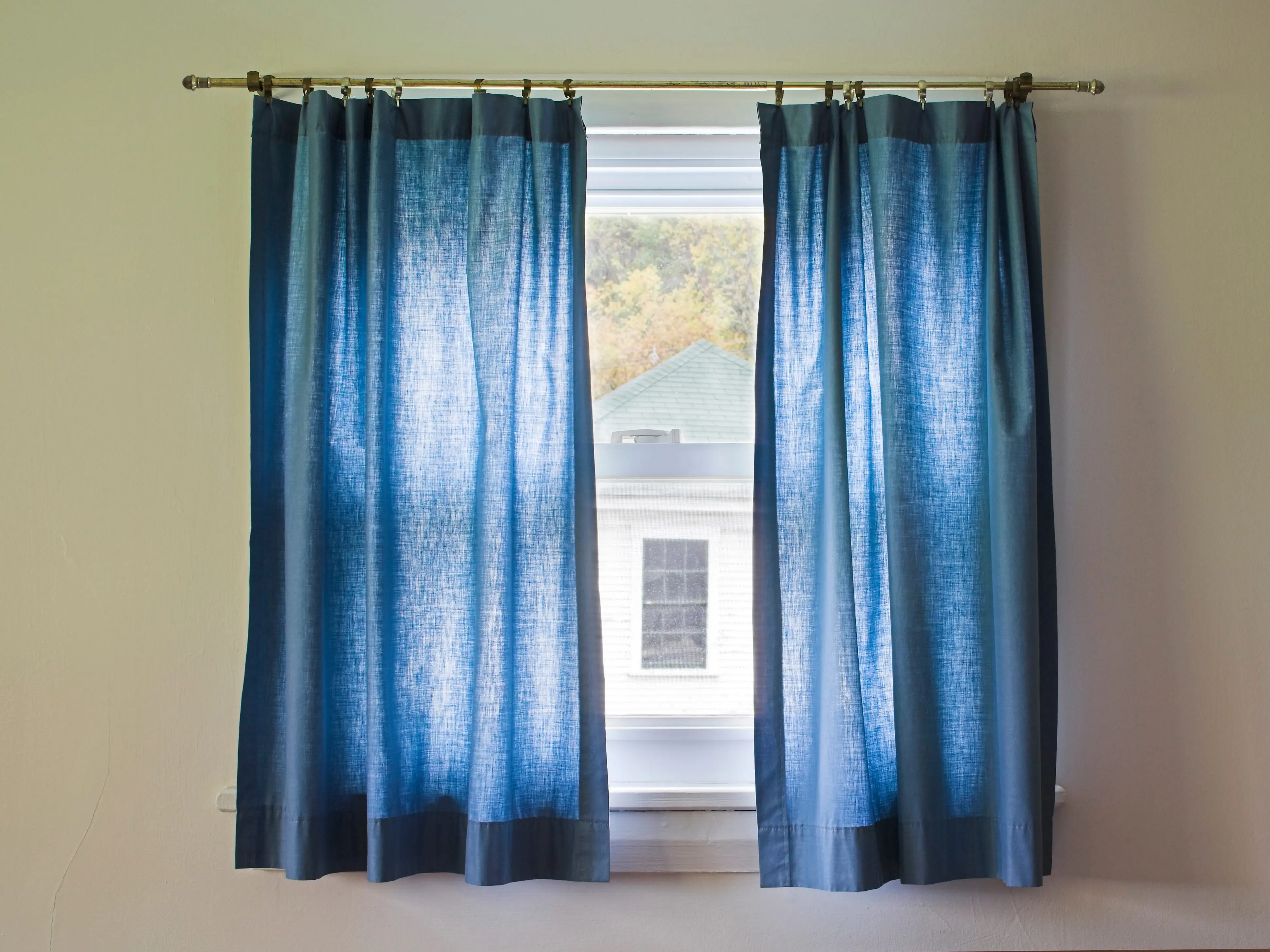 Short, thin, blue curtains on a window.