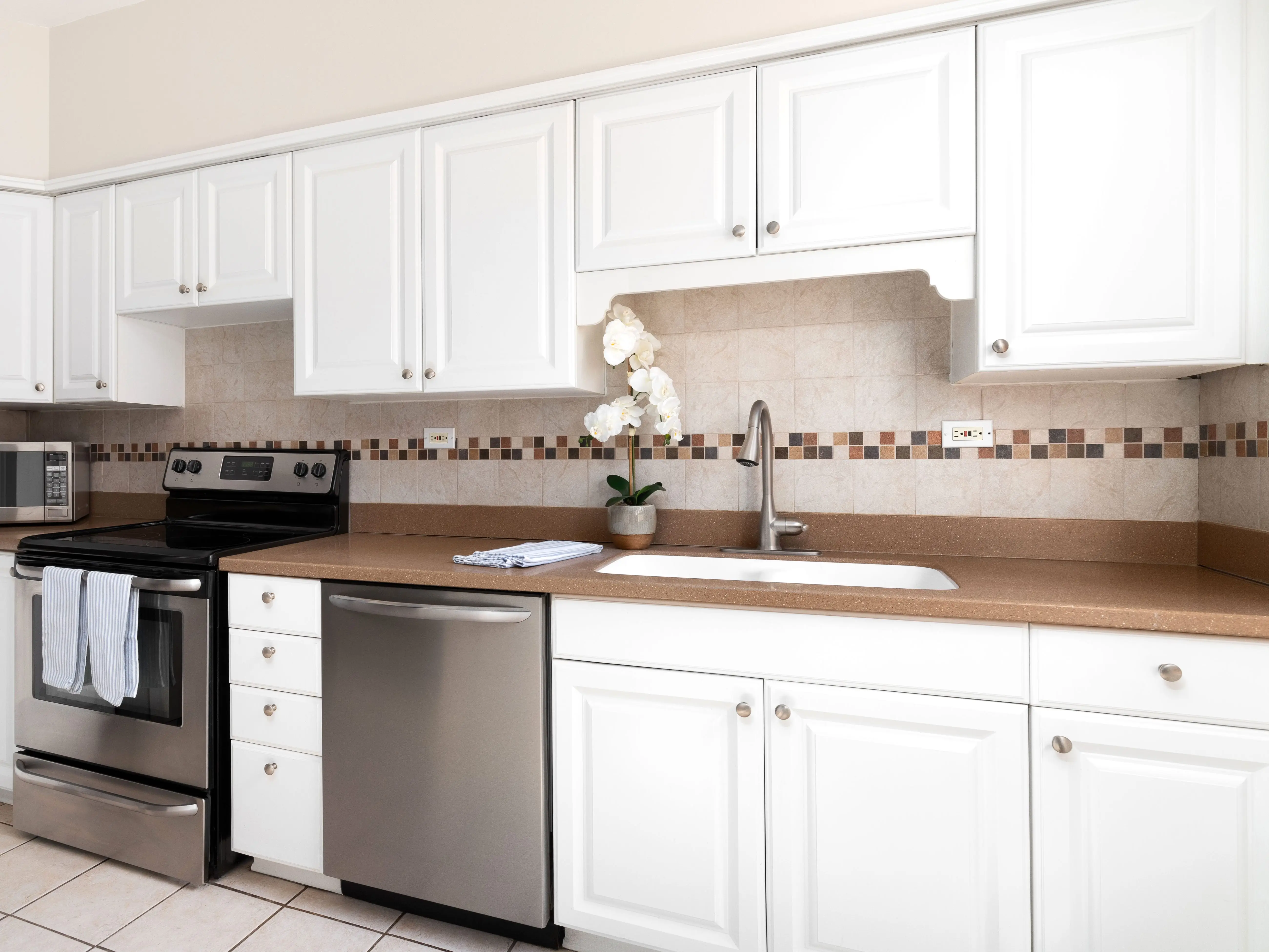 A kitchen with white cabinets and simple silver hardware.