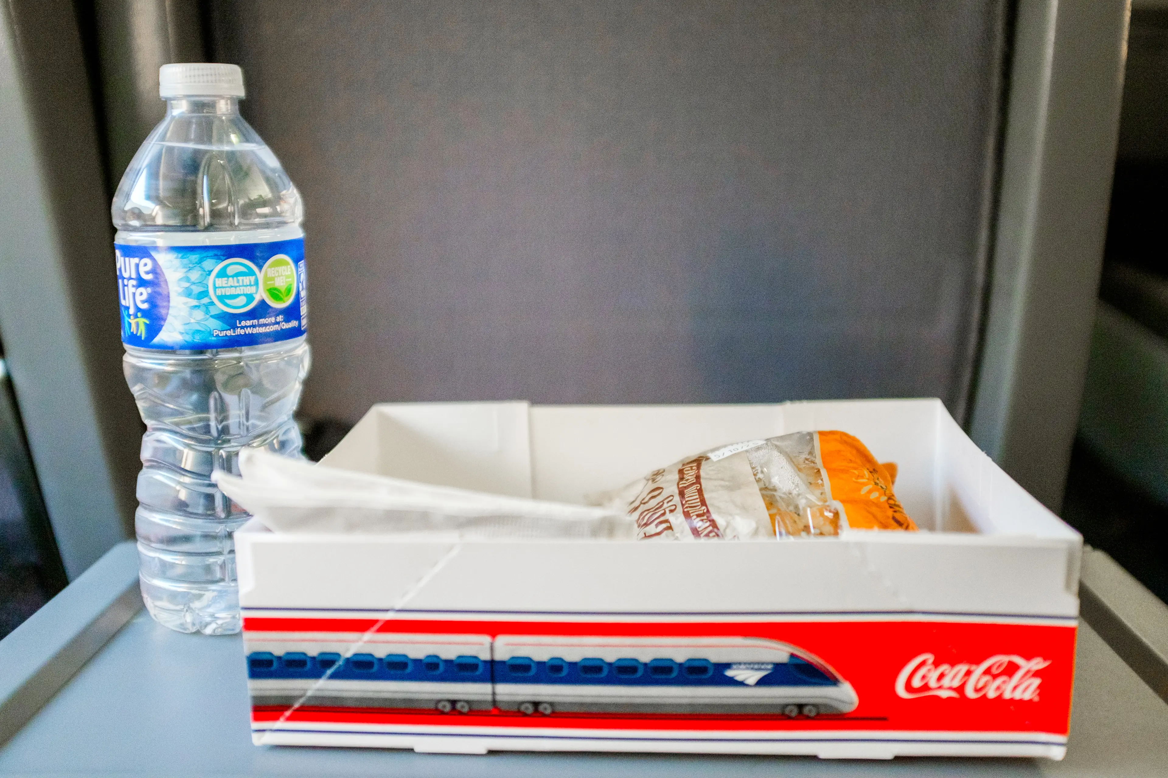 An Amtrak breakfast sandwich and a water bottle on a tray table