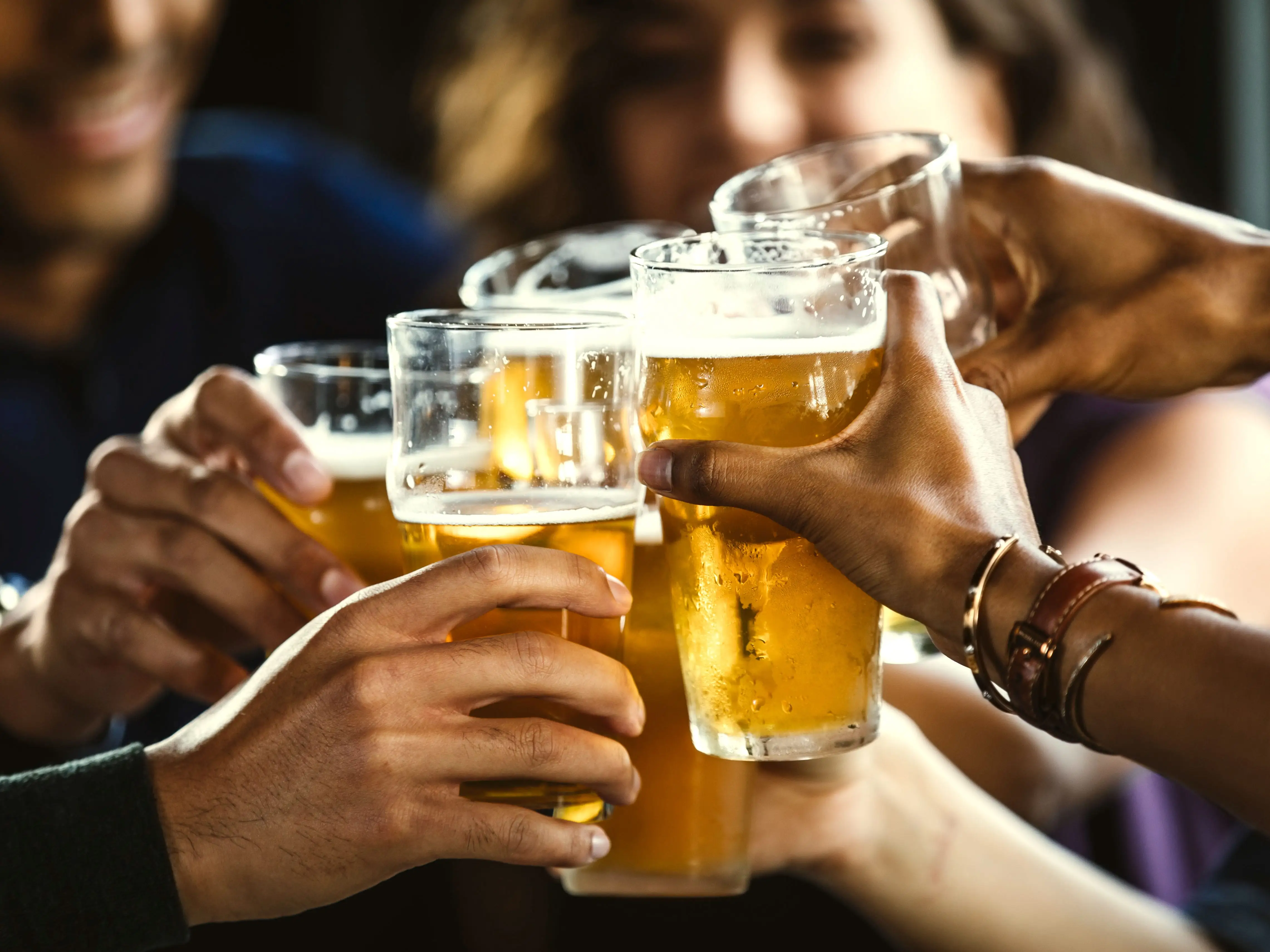 A group of people clinking glasses of beer together.