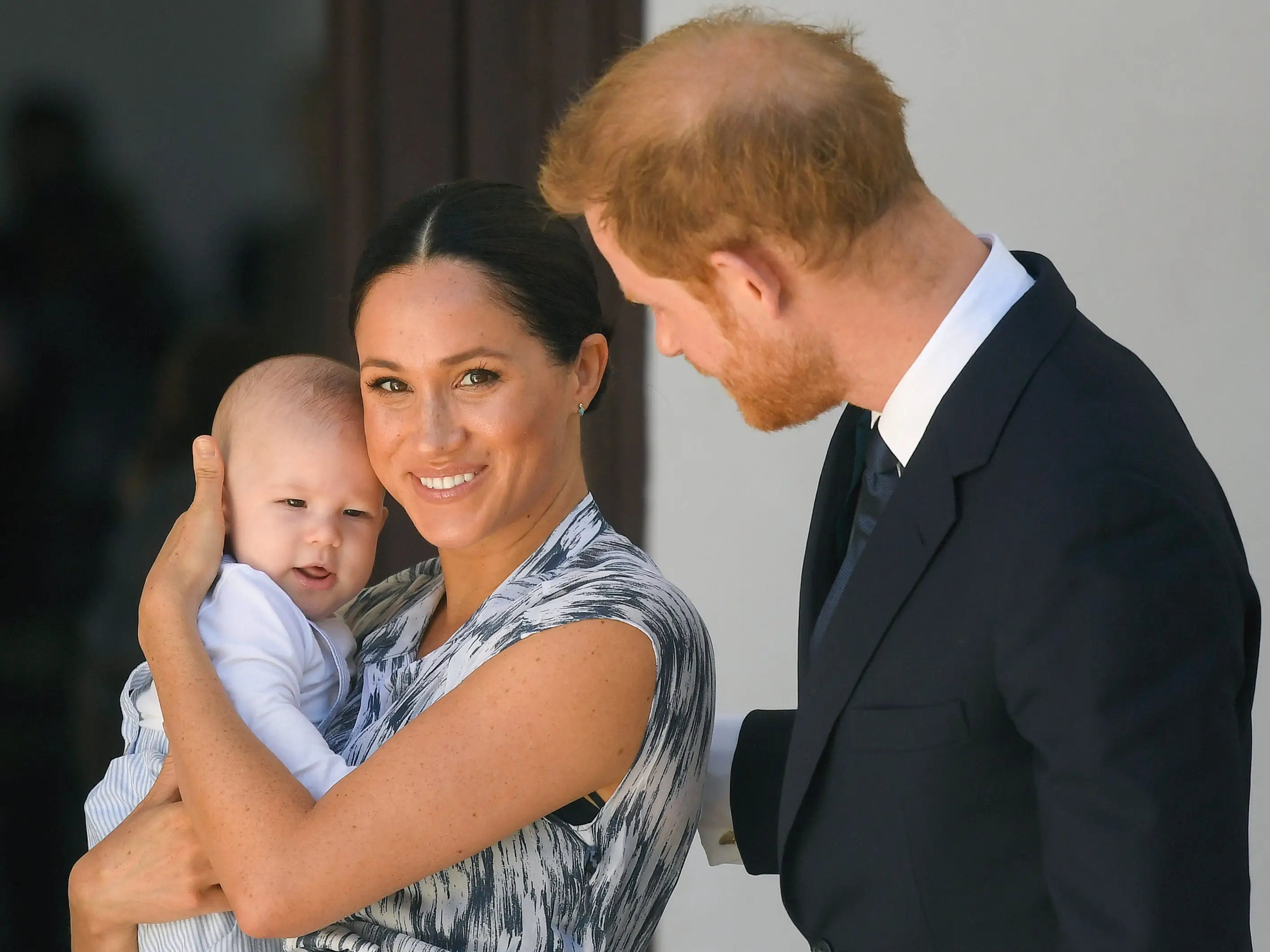 Meghan Markle cradles baby Archie while Prince Harry leans in.