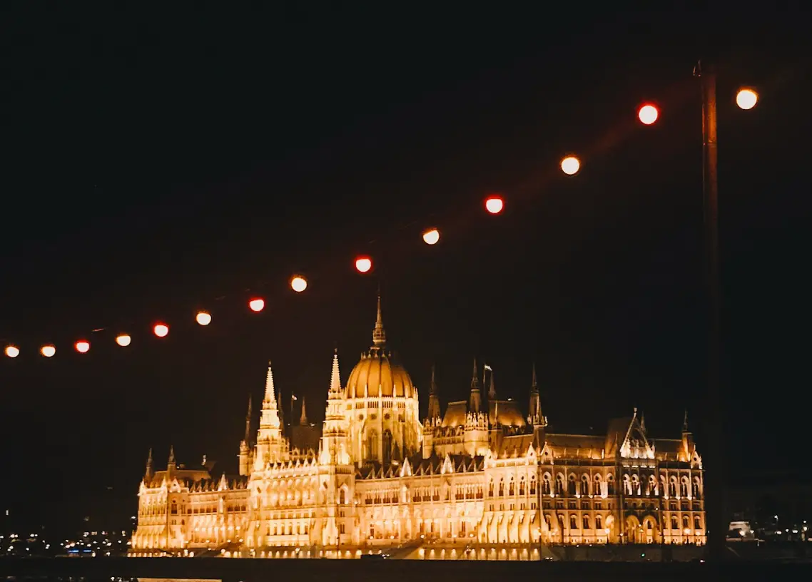 A view of the lit-up Hungarian Parliament Building from a Budapest river cruise at night.