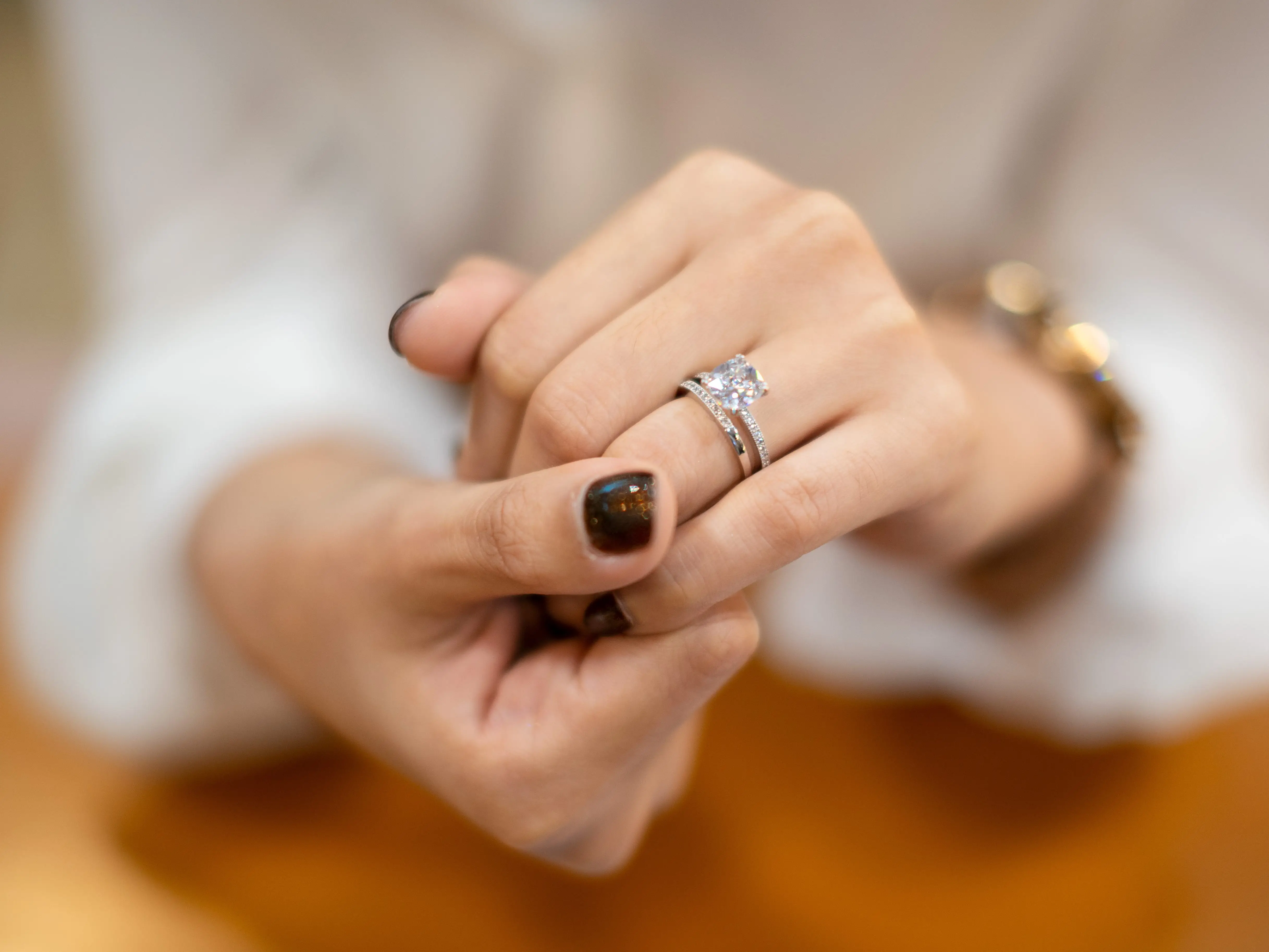 An engagement ring and wedding band on a hand. Both are covered in small diamonds.