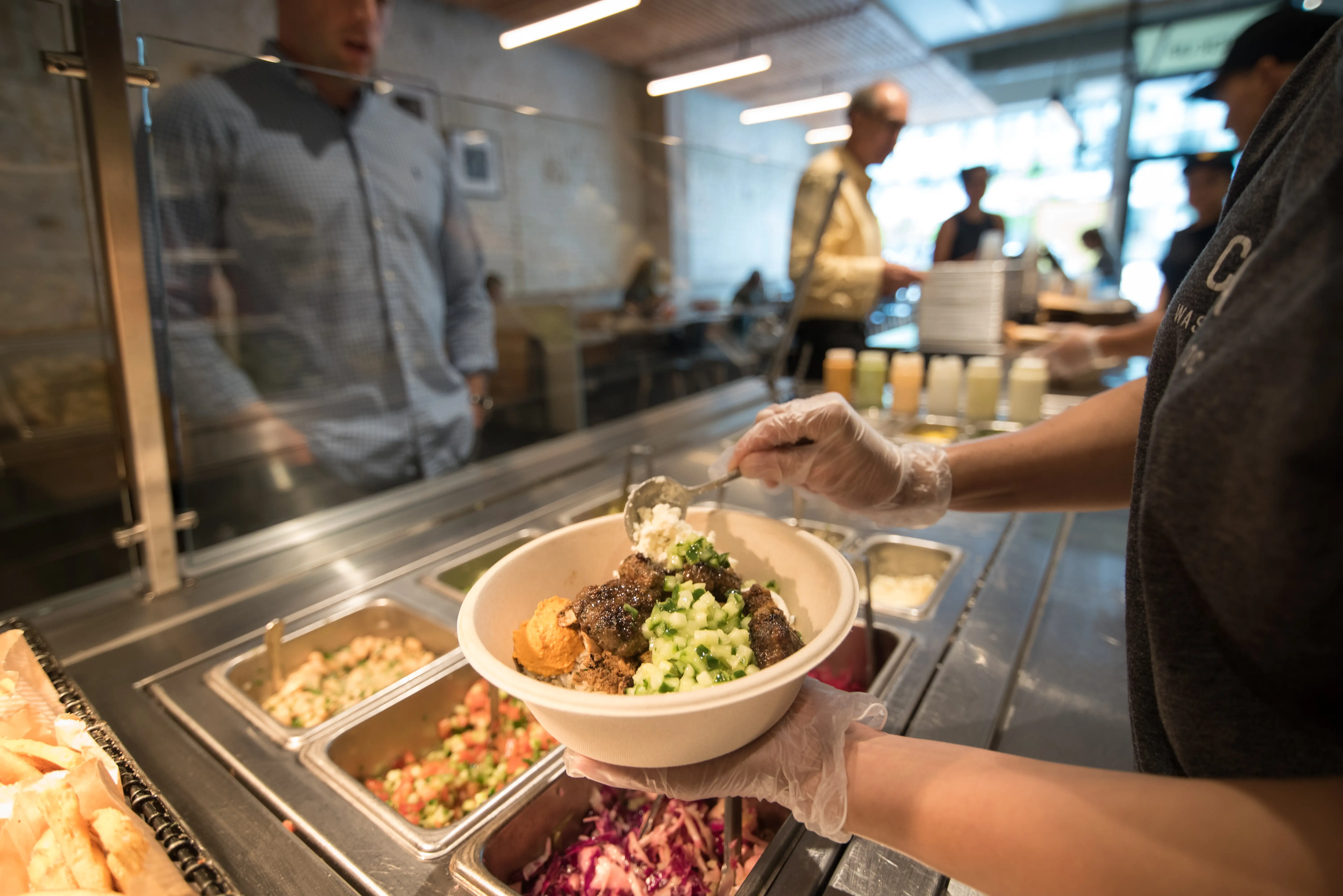 A customer selects dip and spread for his bowl at Cava.