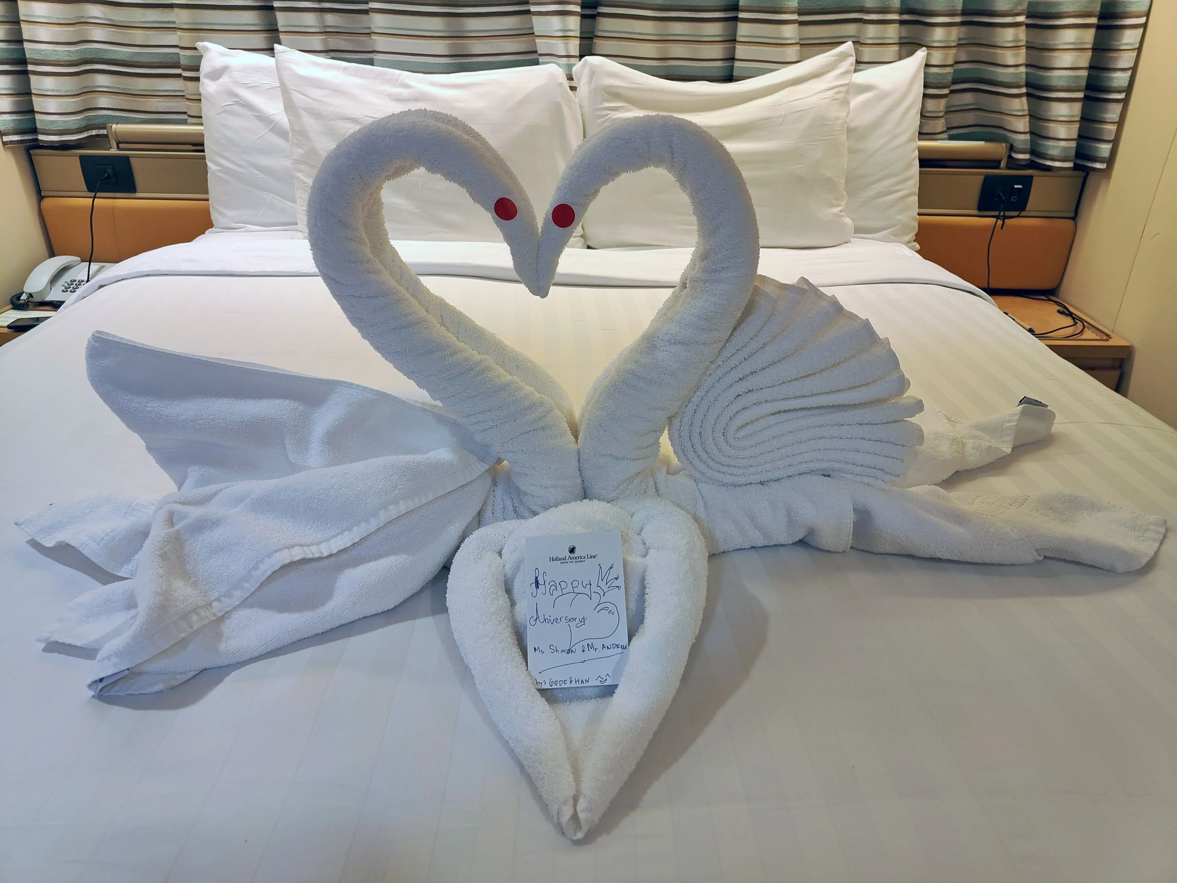 Towels folded into swans on a bed, with a note that reads 