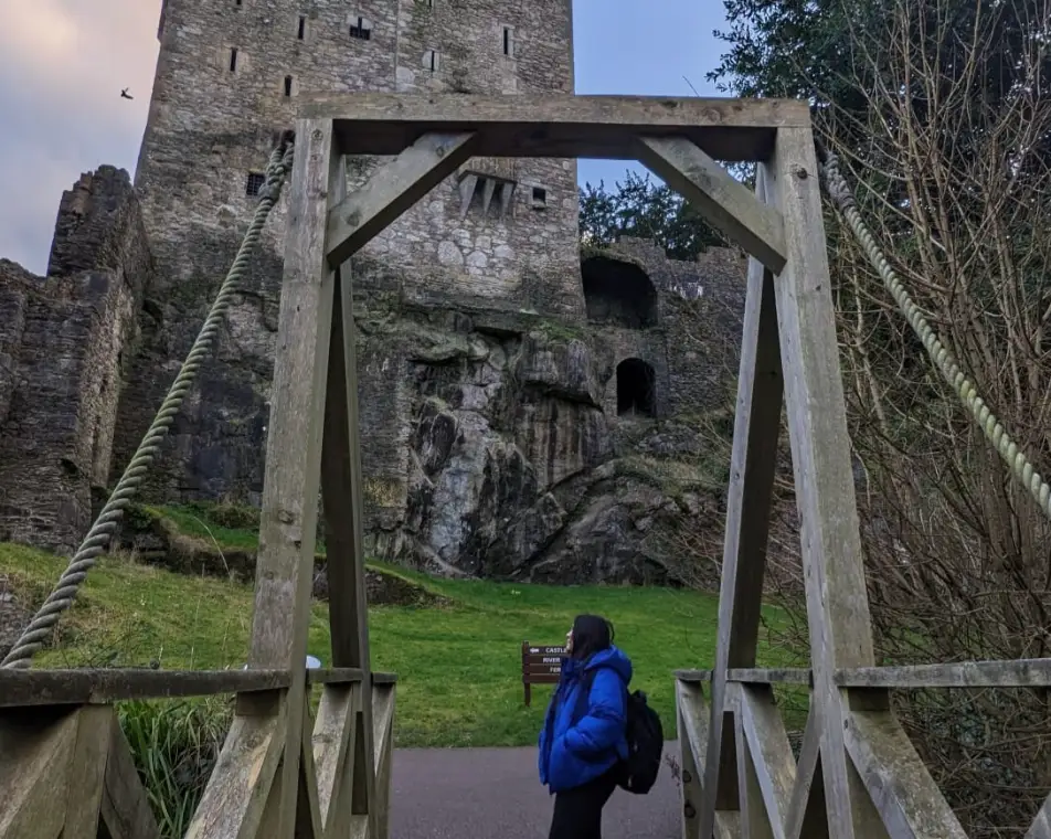 The writer posing in front of Blarney Castle, wearing a bright blue coat.