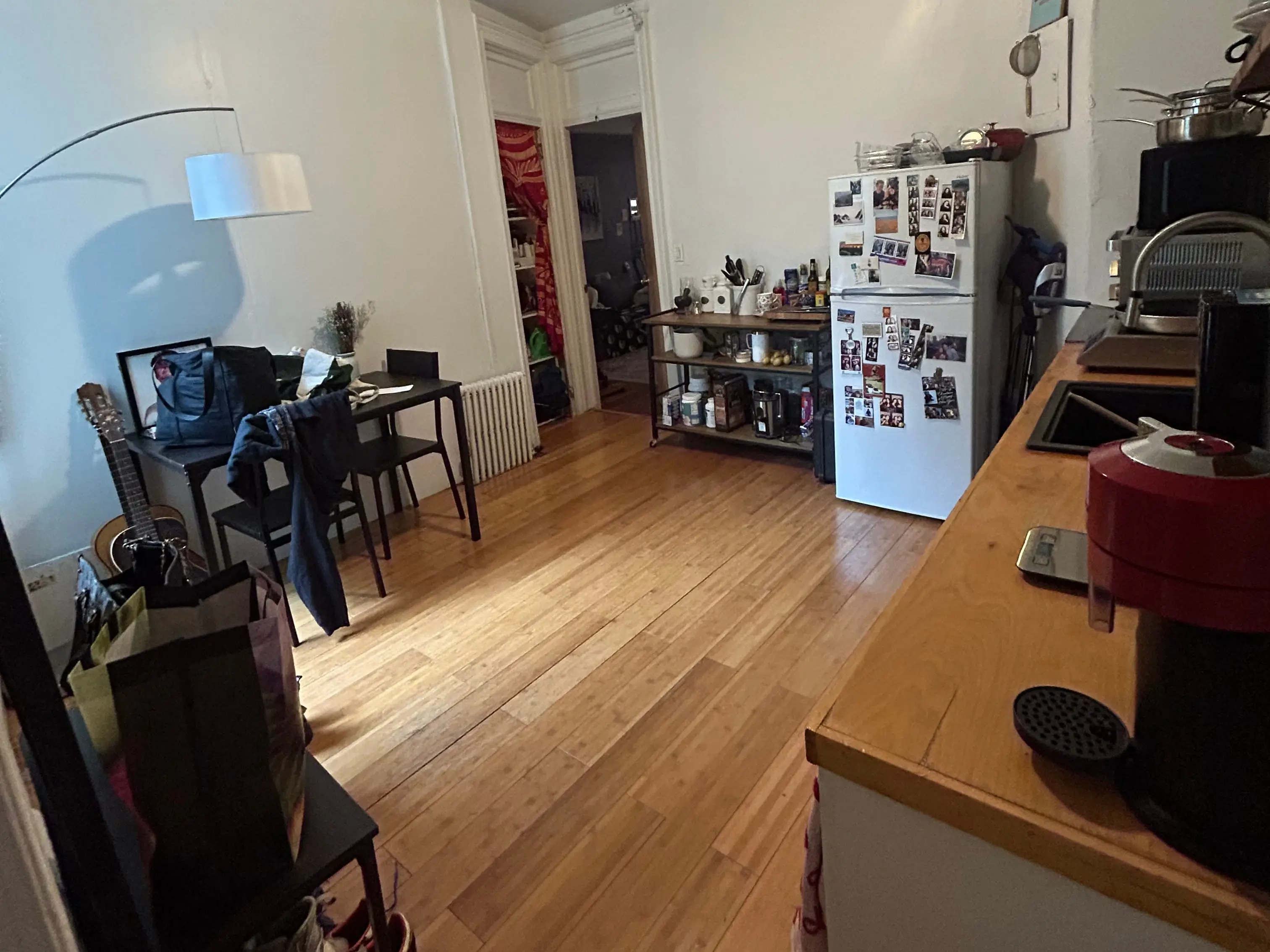 Kitchen with white fridge, small table, wood floors, white walls