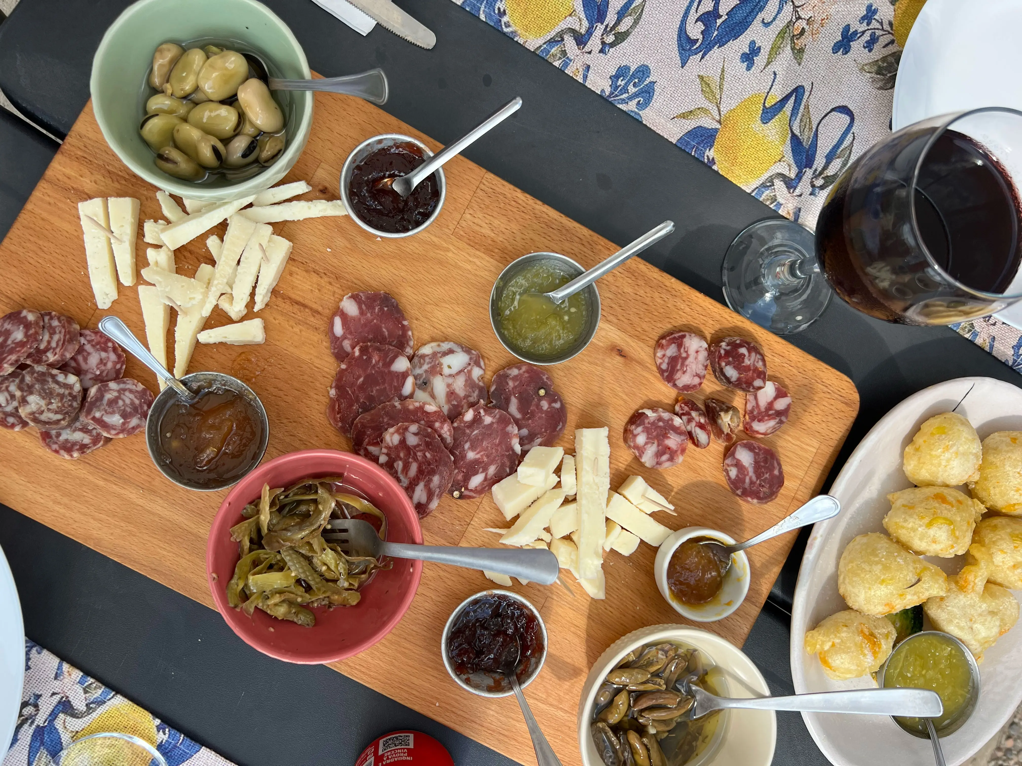A charcuterie board of meats, cheeses, peppers, olives, and jams.