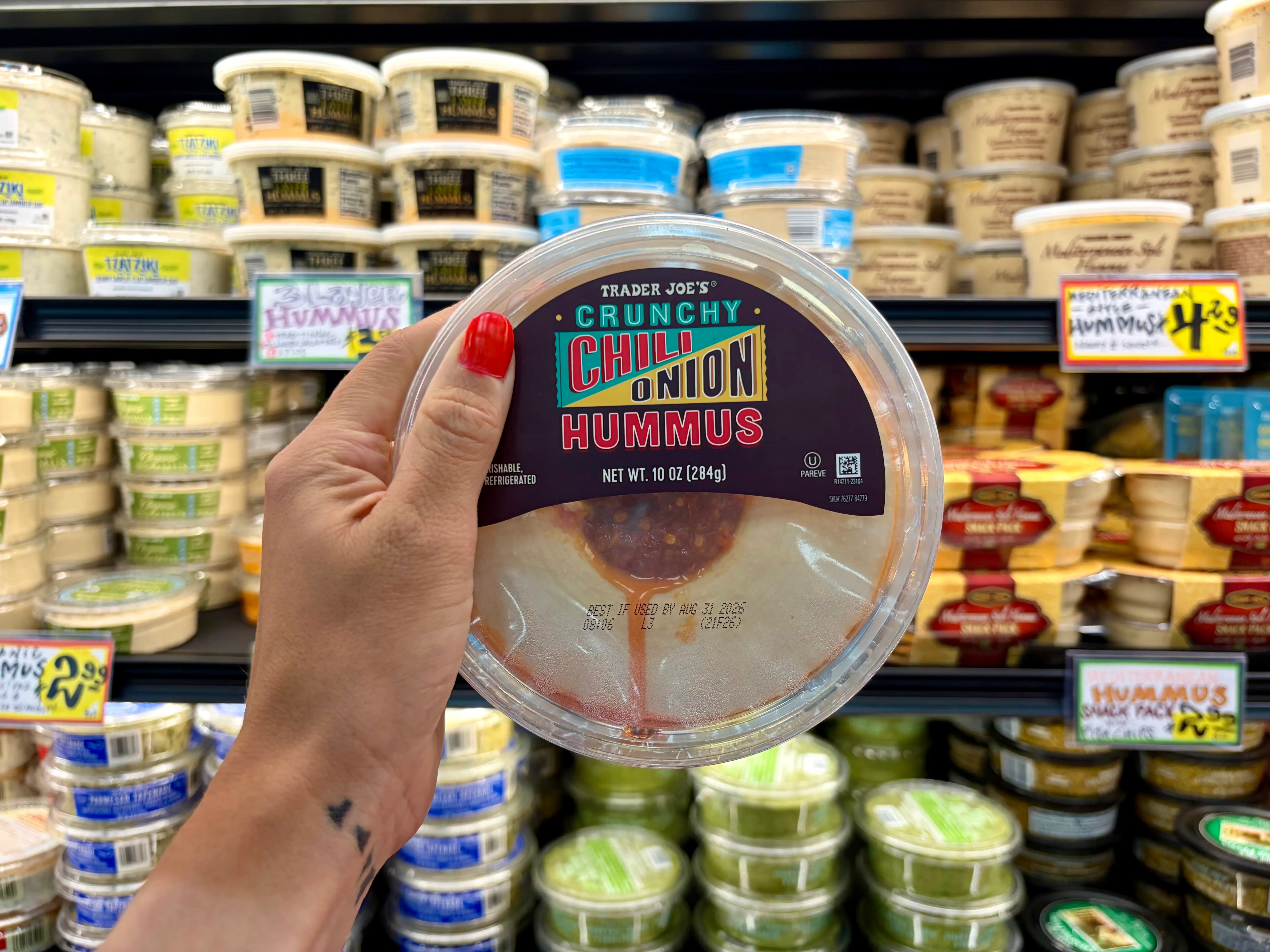 Emily holding a container of Trader Joe's crunchy onion hummus.