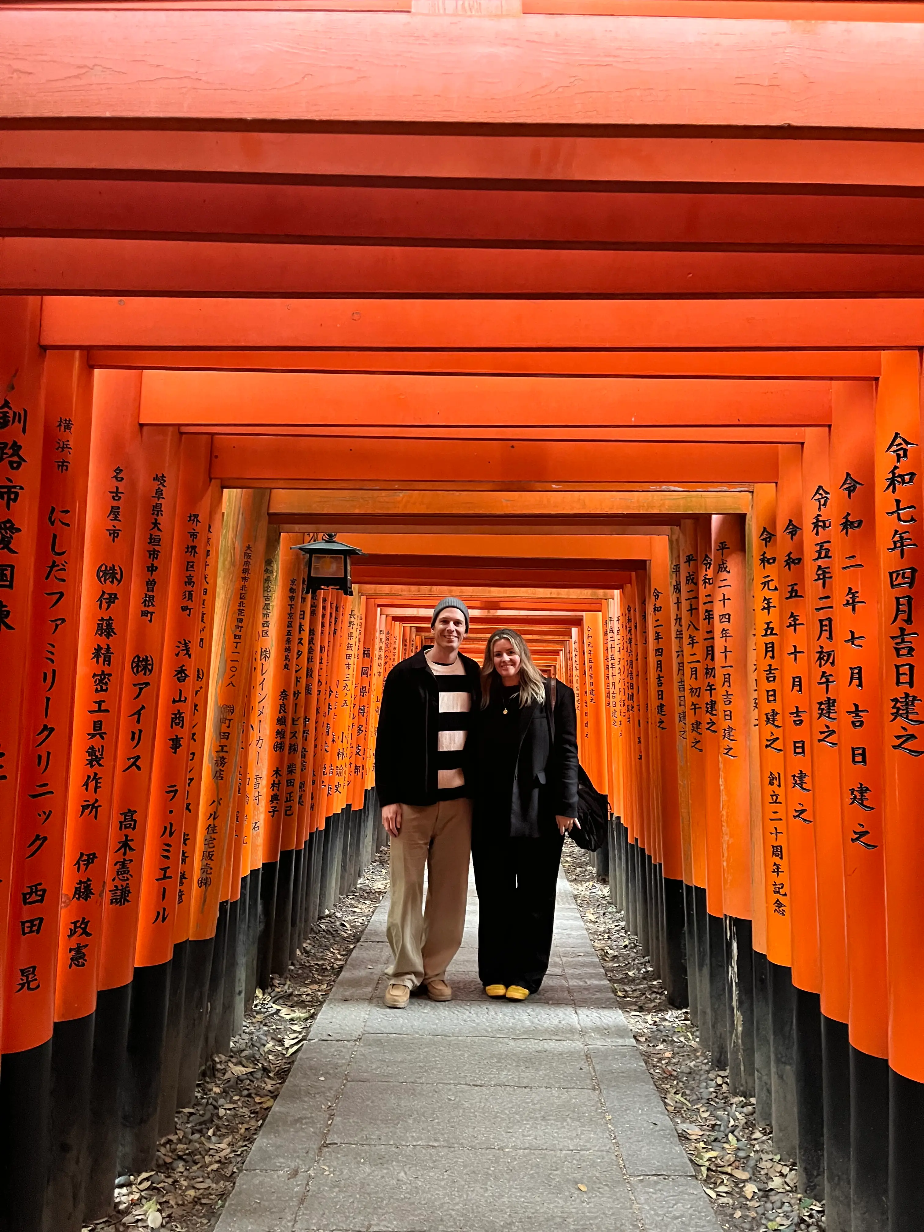 A couple standing under the Torii gates in Japan.