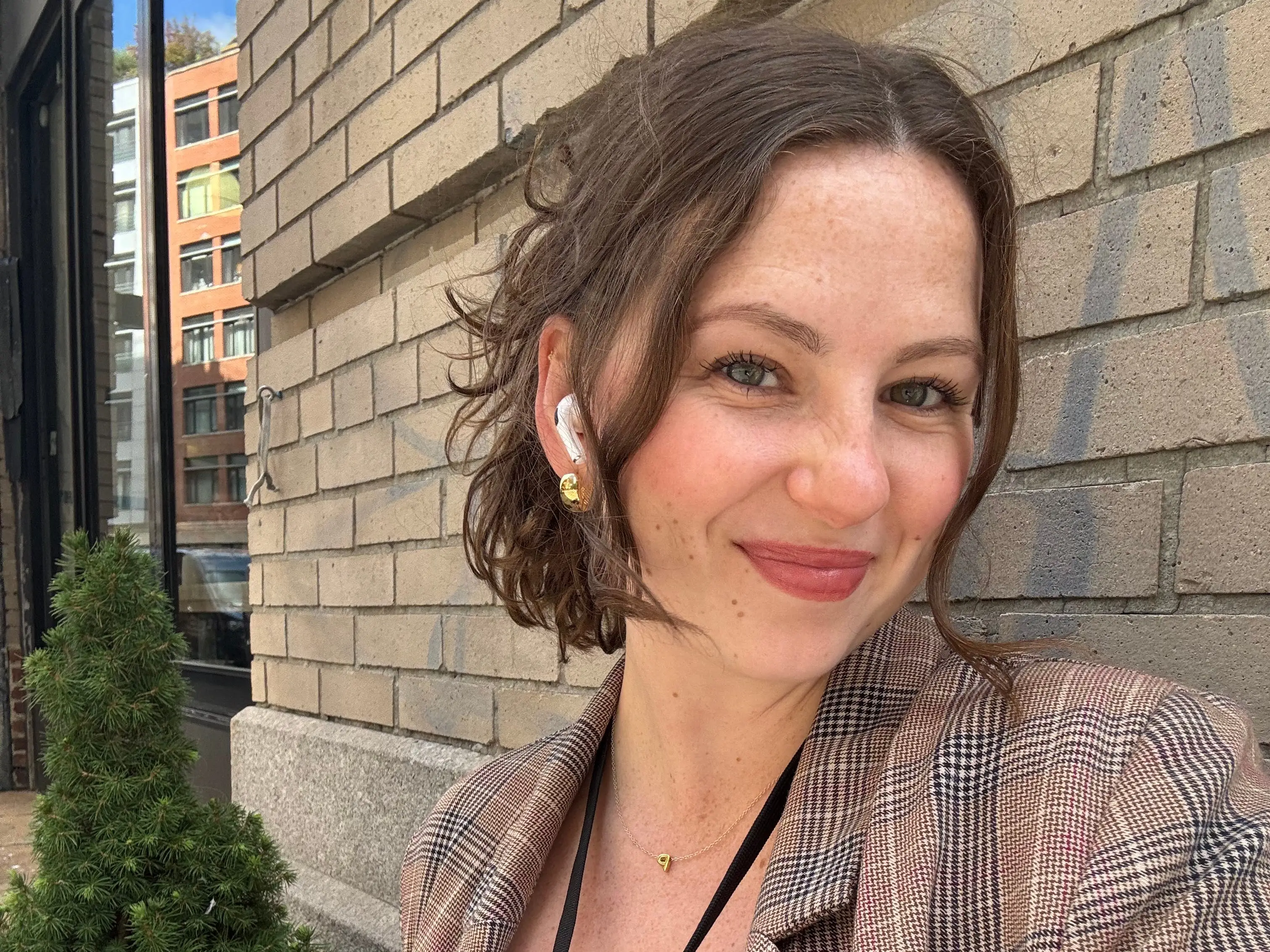 A woman smiles in front of a brick wall.