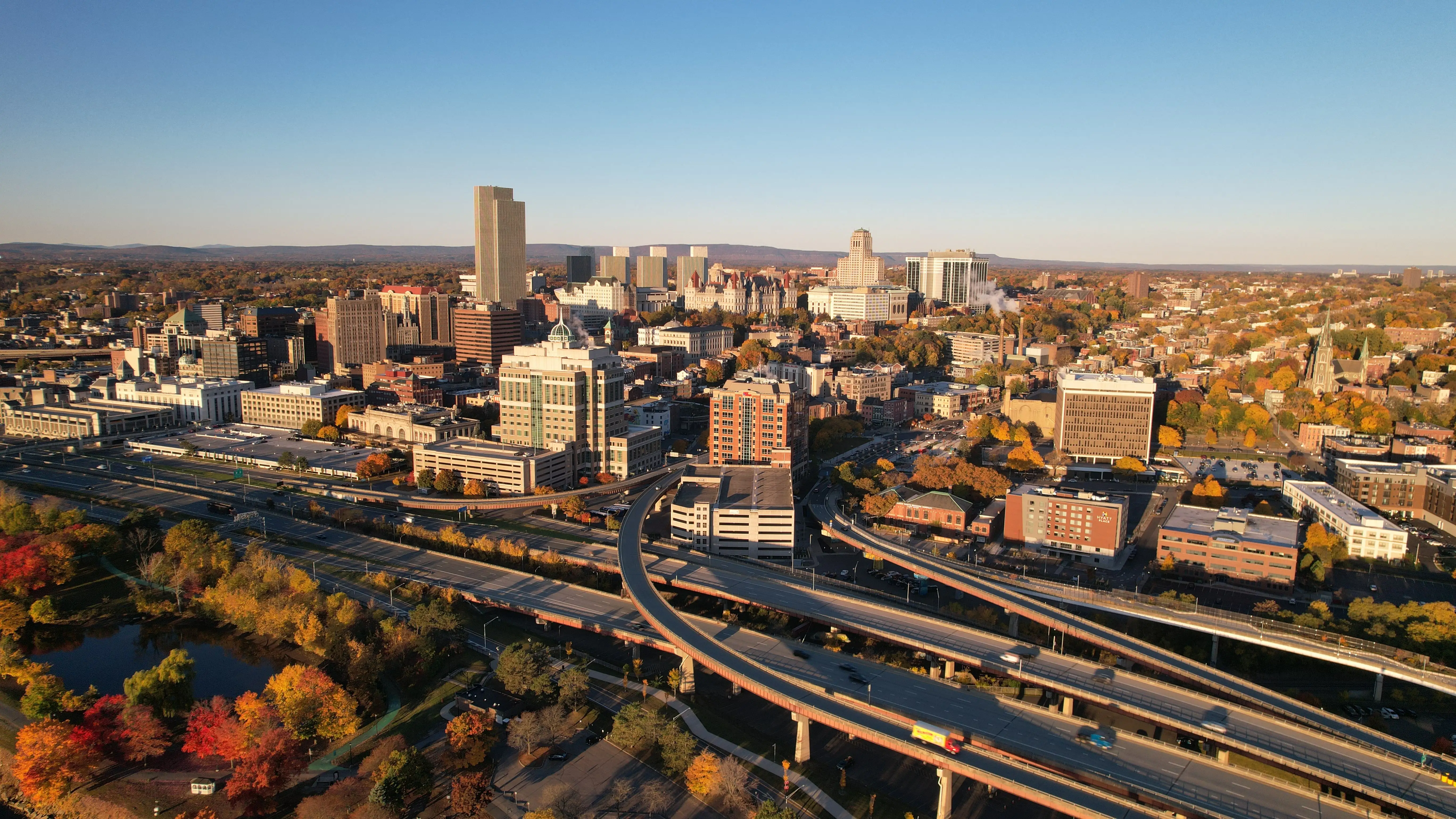 An aerial view of Albany, New York skyline during autumn with vibrant foliage and clear blue sky