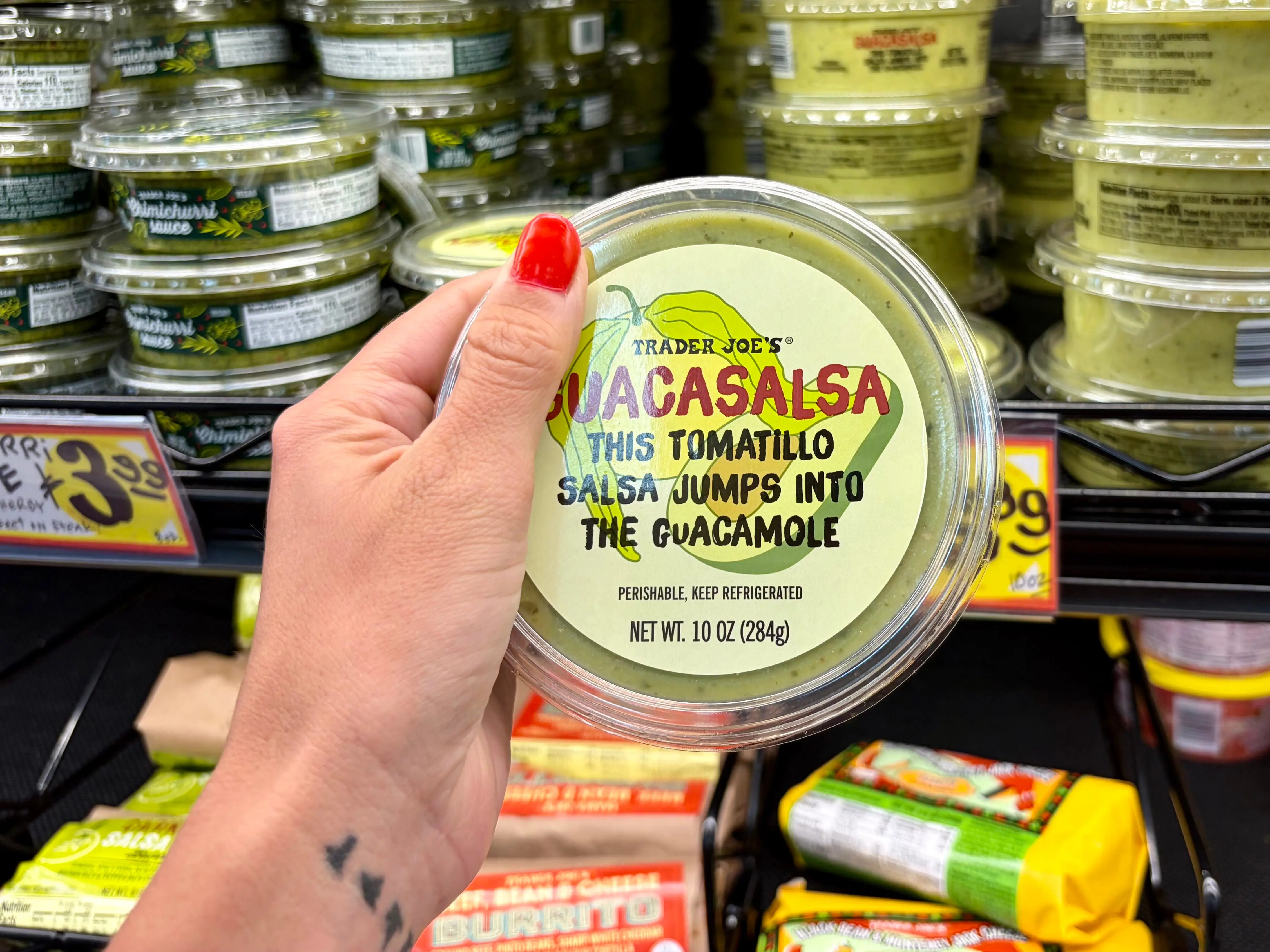 Emily holding a container of Trader Joe's guacasalsa.