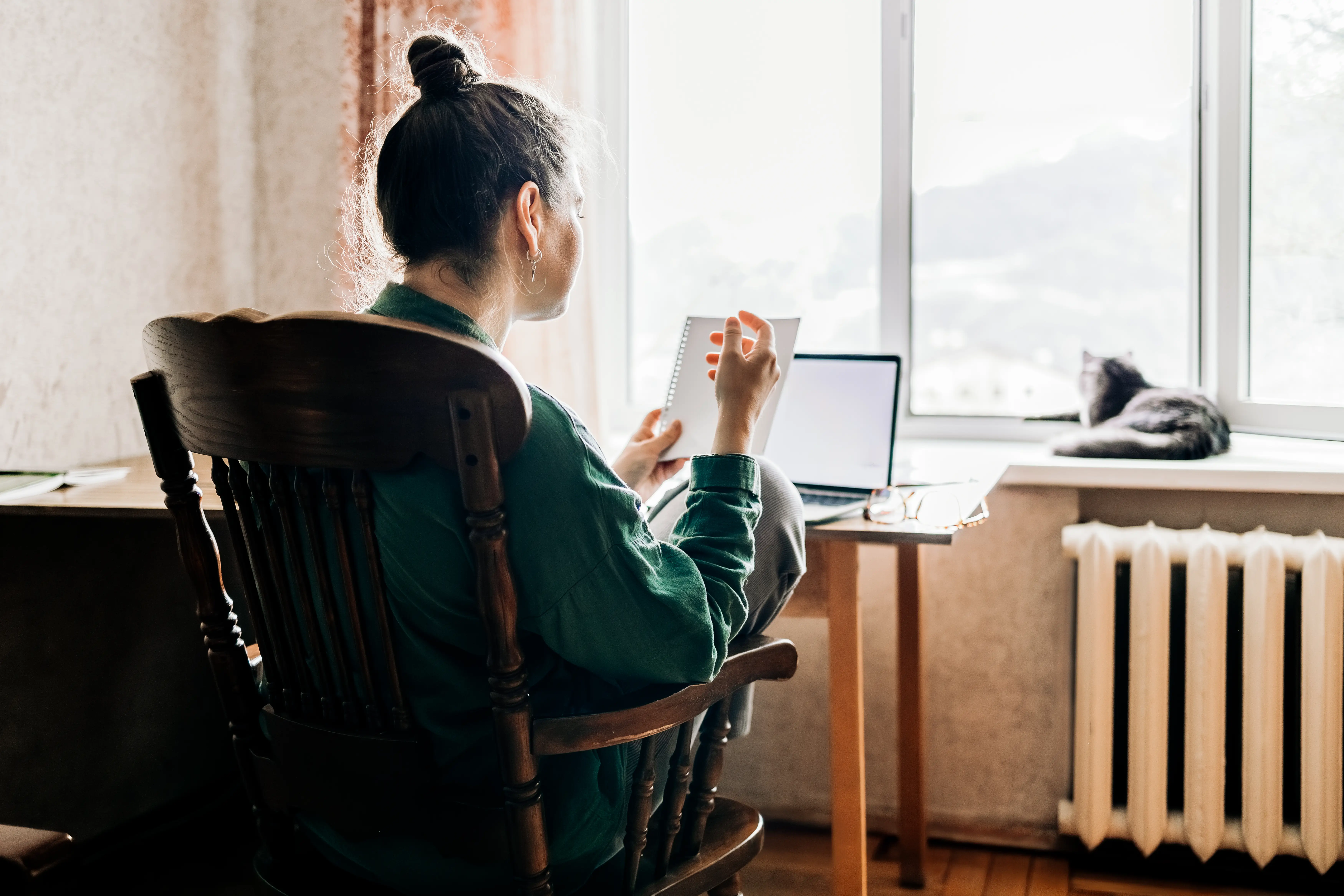 A woman looking at a piece of paper at home desk