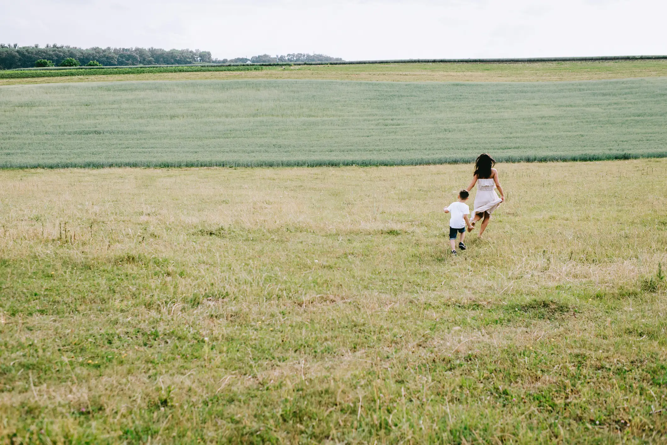 Rear view of mother and son running in field