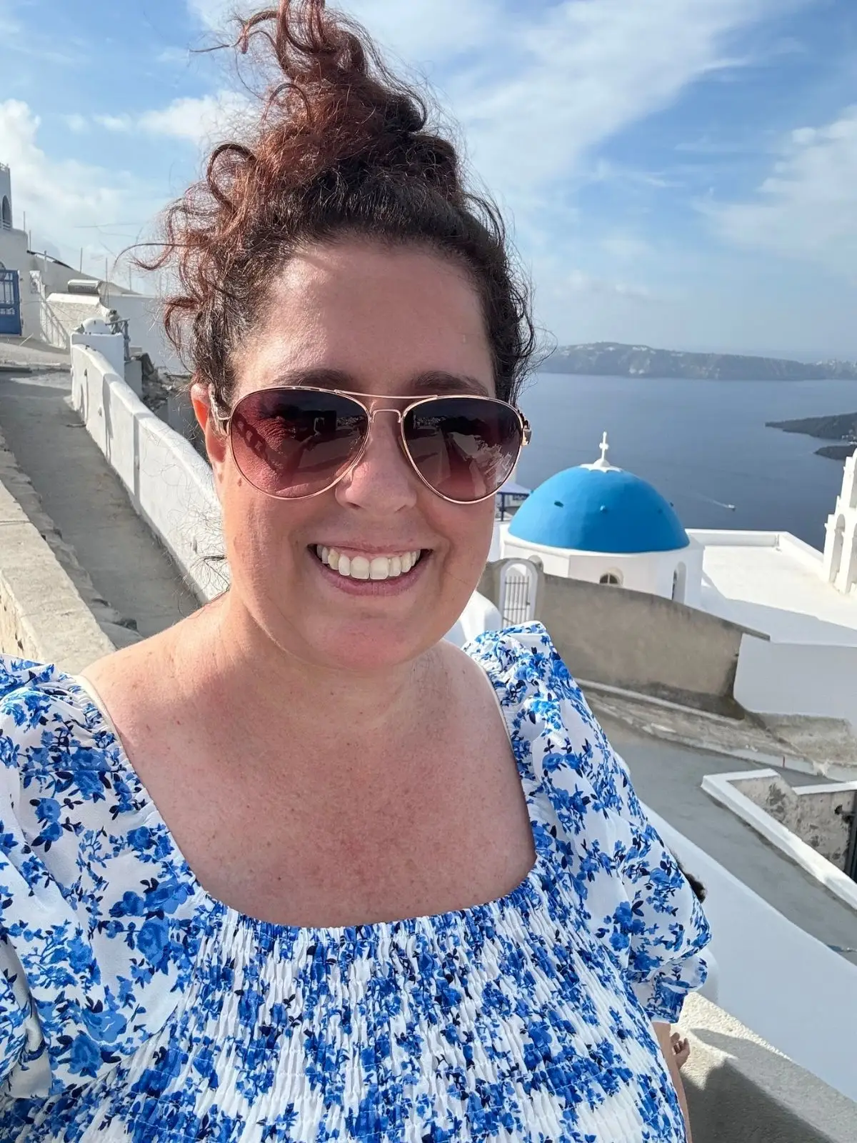 Woman smiling near blue-domed church in Santorini