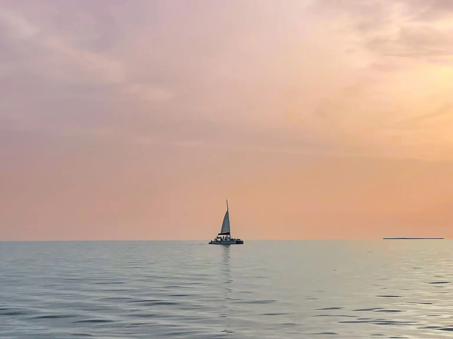 A sailboat in the water at sunset.