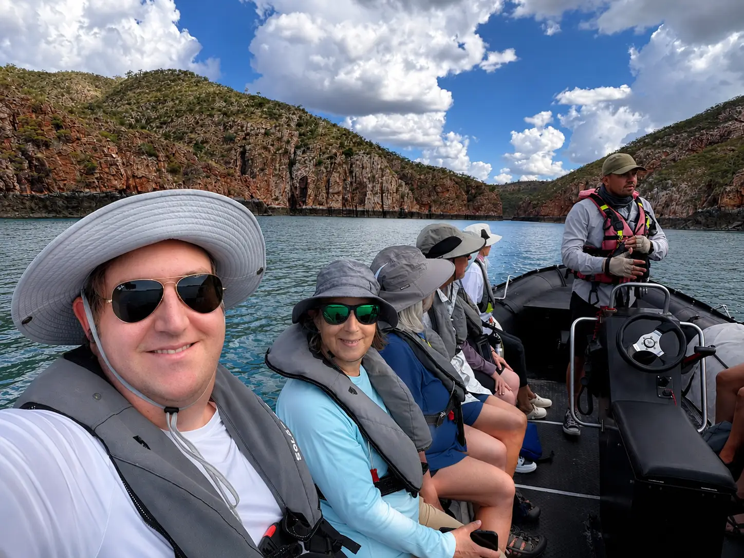 Man and woman in vests and hats smiling on boat in water