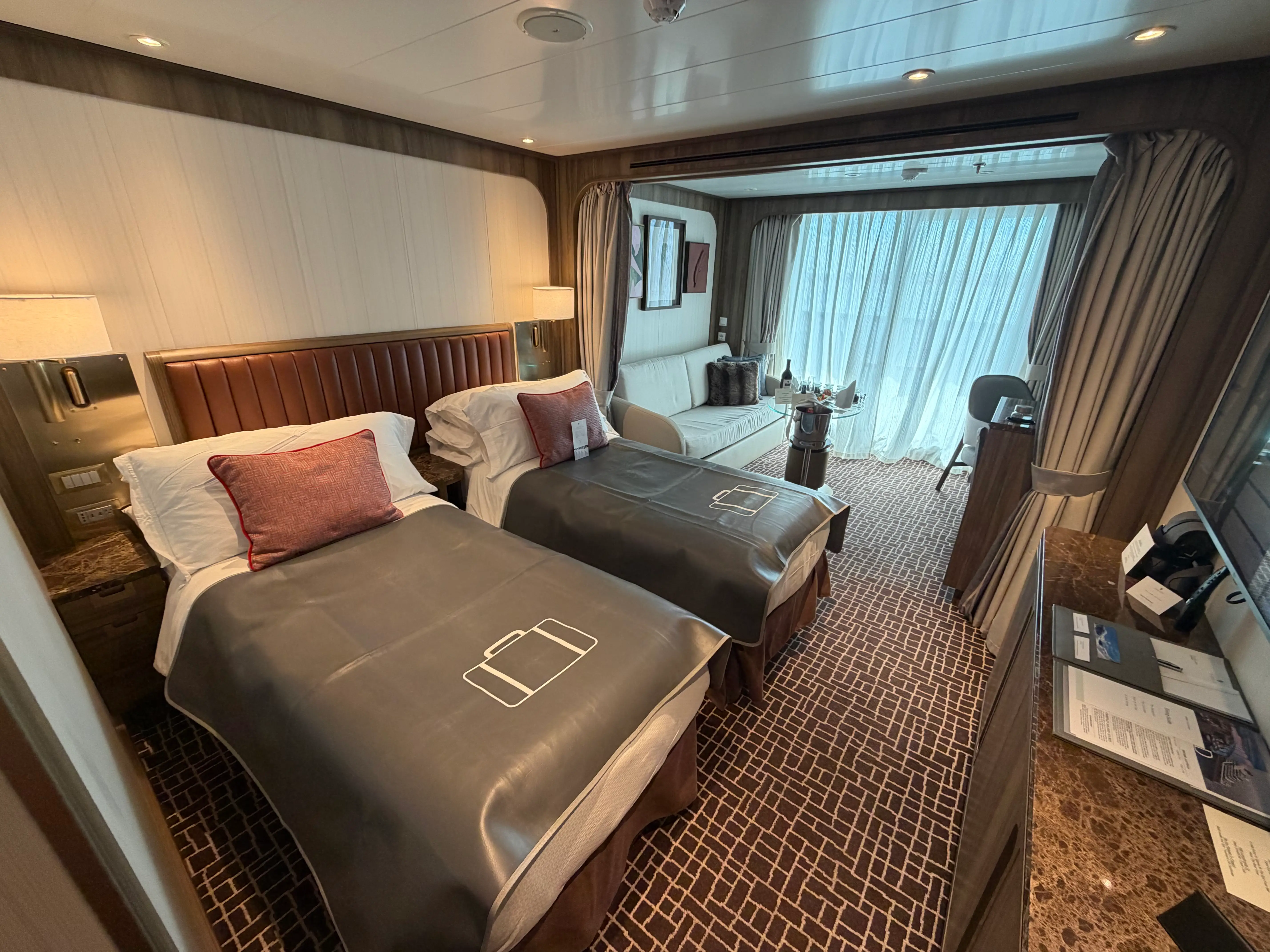 Room on Seabourn cruise ship with two beds, floor-to-ceiling glass, carpeting