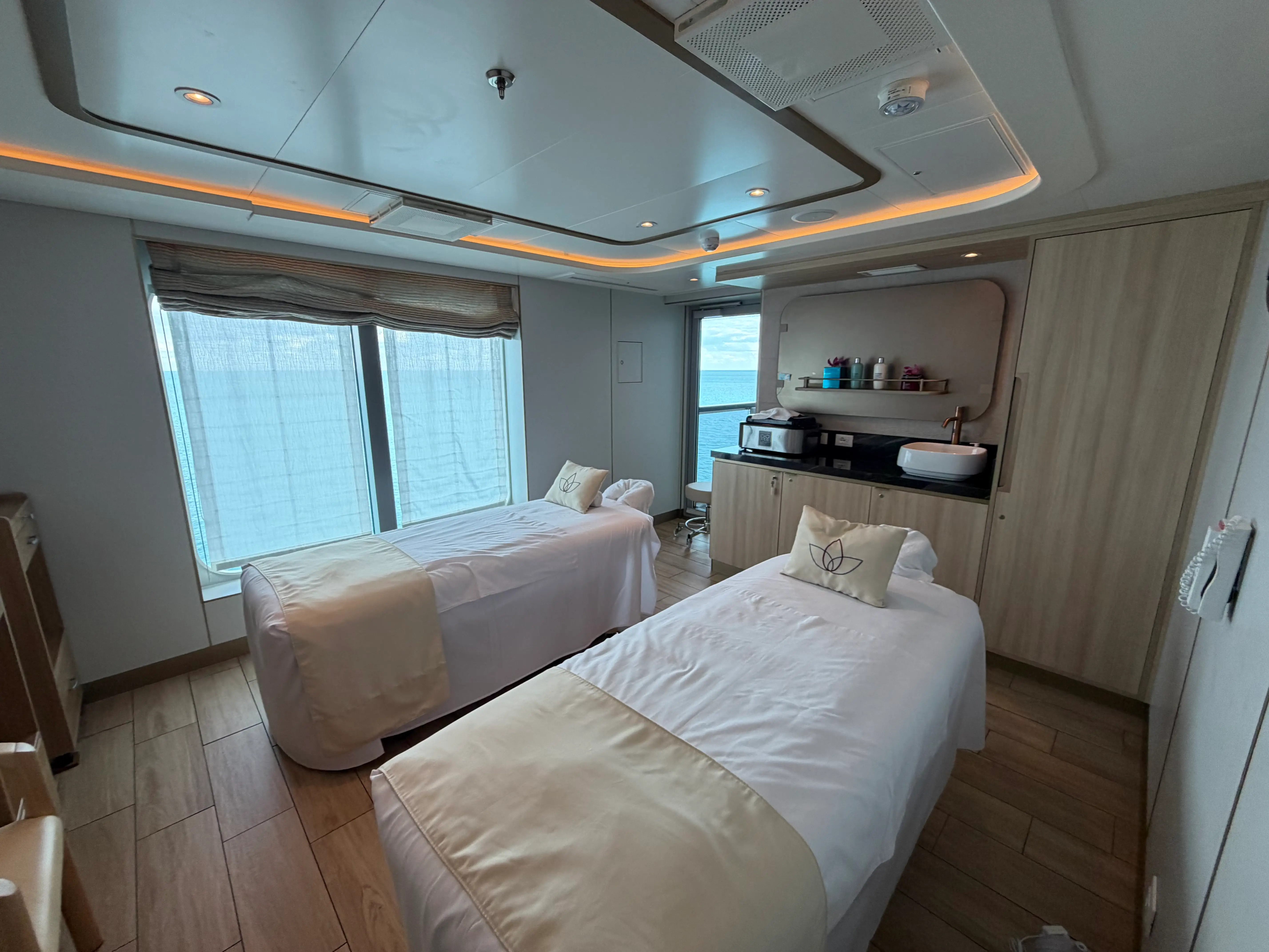 Two white beds in spa-like area with cabinets behind them