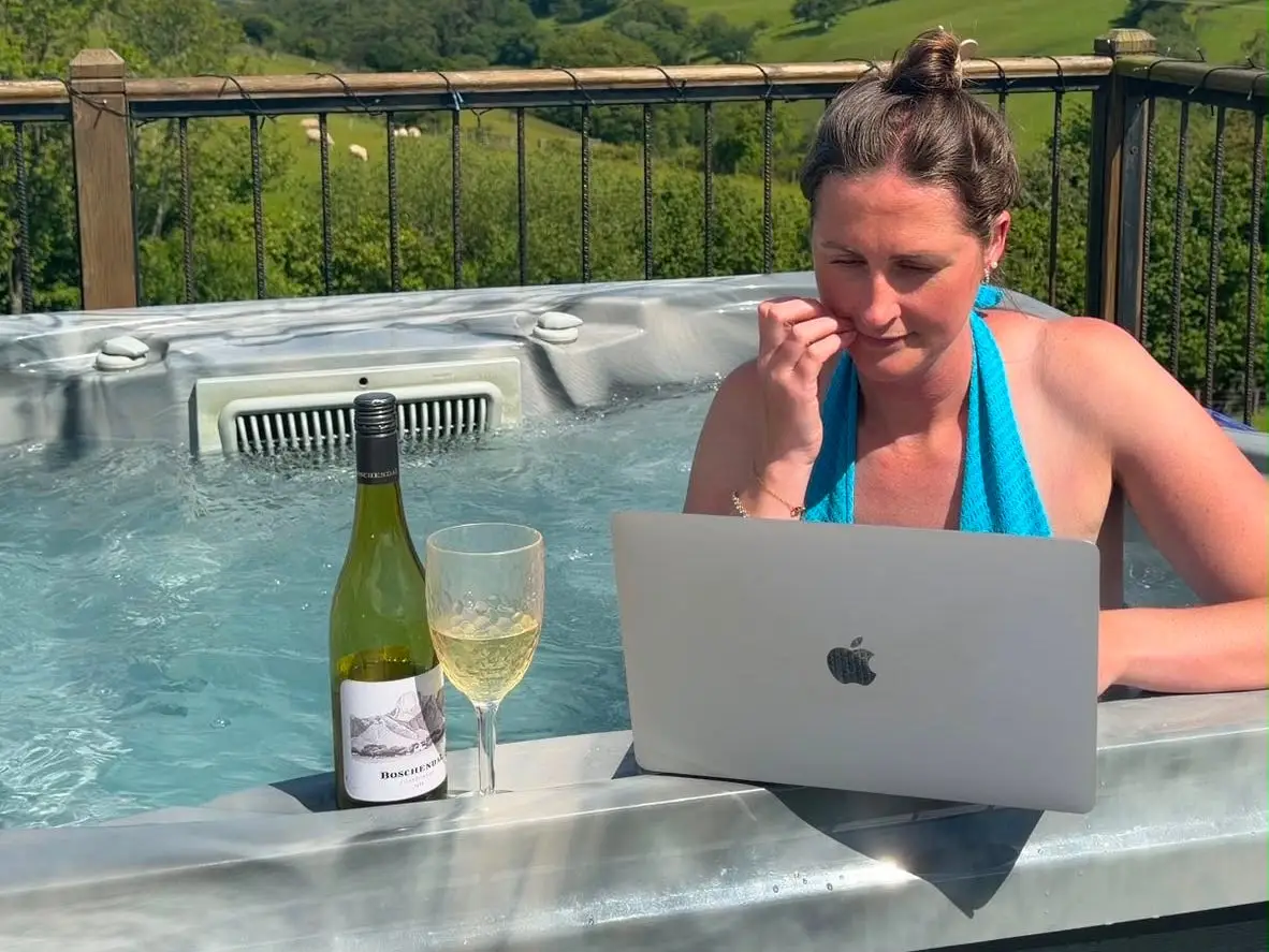 Abbie Manning sits in a hot tub while working and drinking champagne.