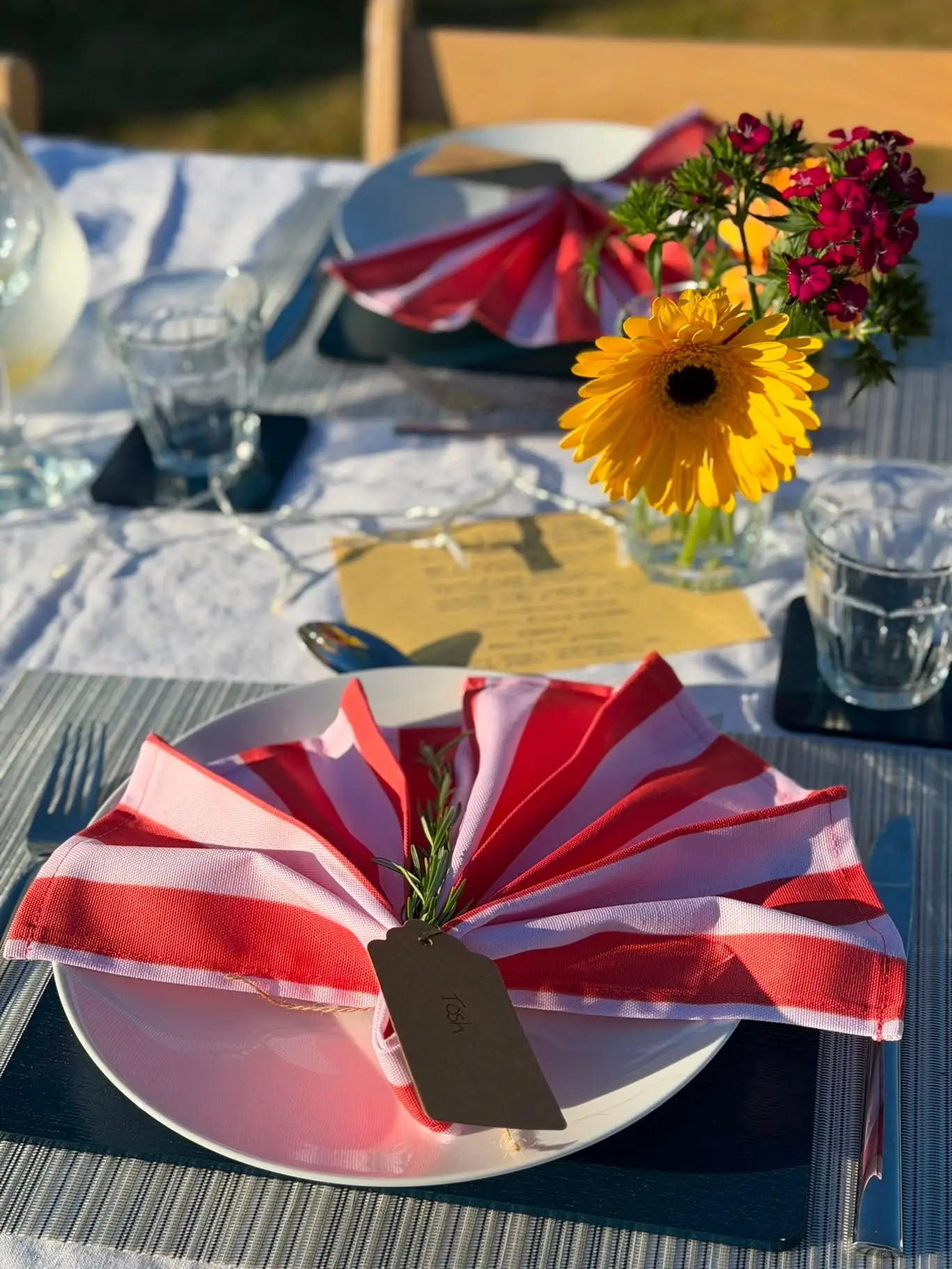 Plating on a table with flowers, name cards, and napkins.