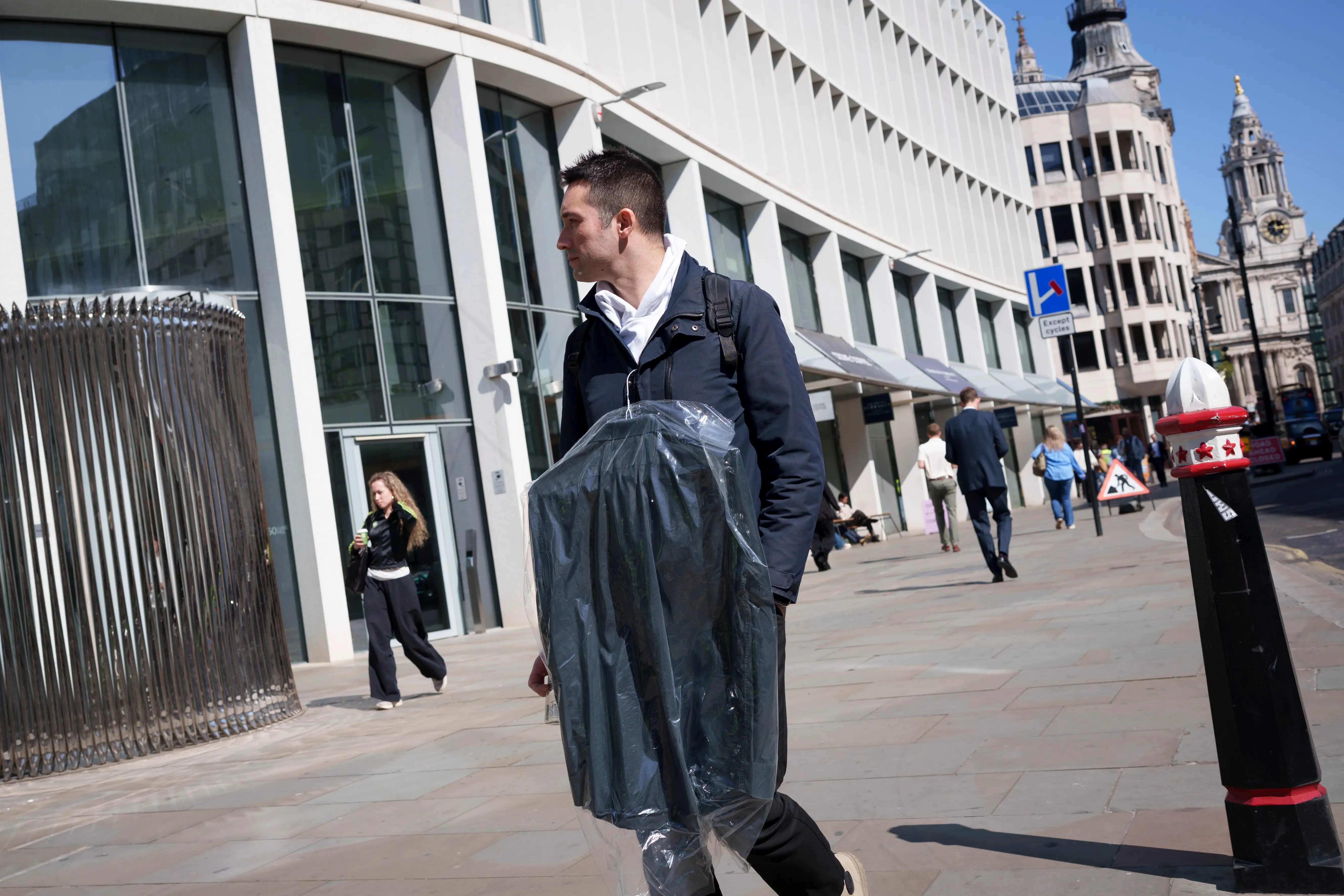 A City worker in London carrying his dry cleaning.