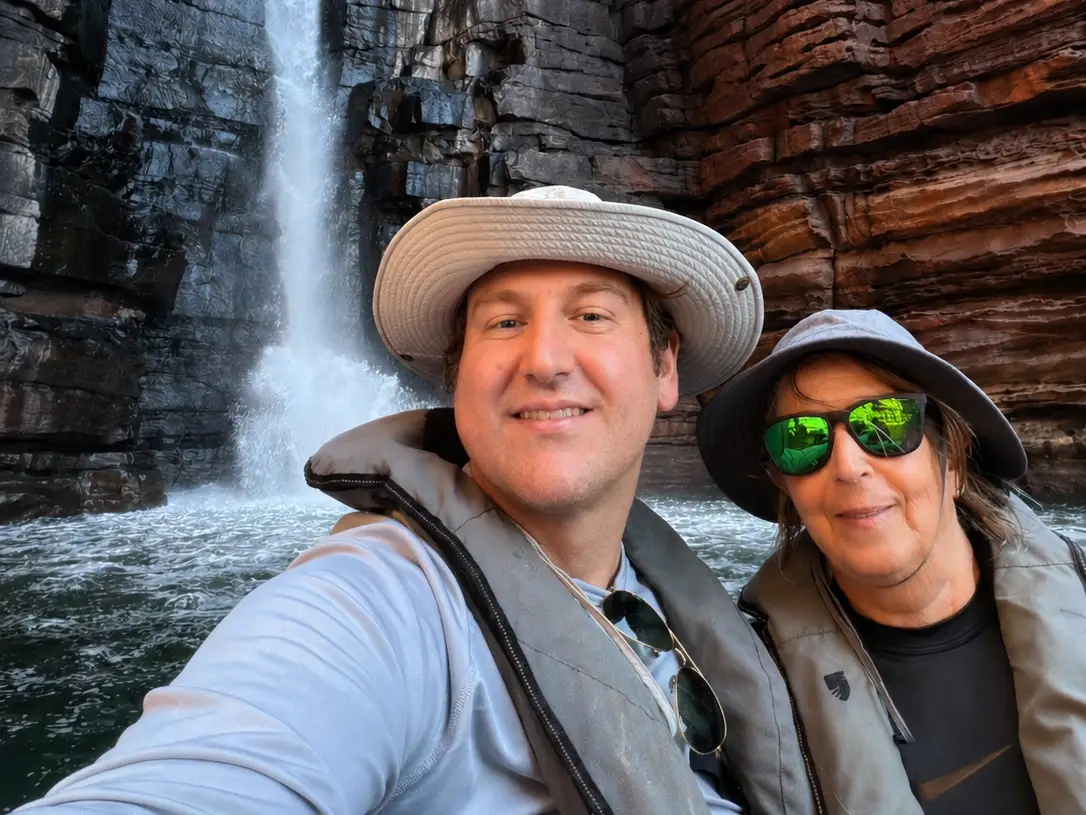 Man and woman smiling in front of water falls