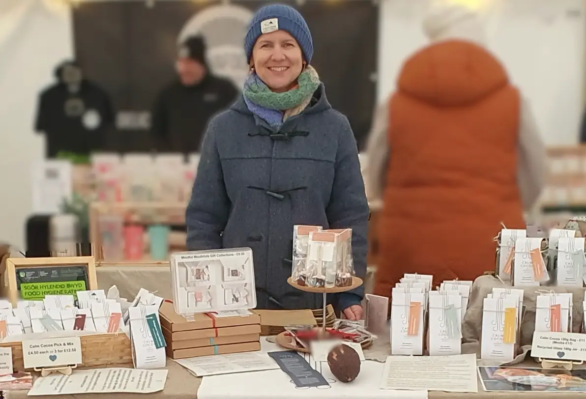 The writer standing in front of chocolates at a winter market in Wales.
