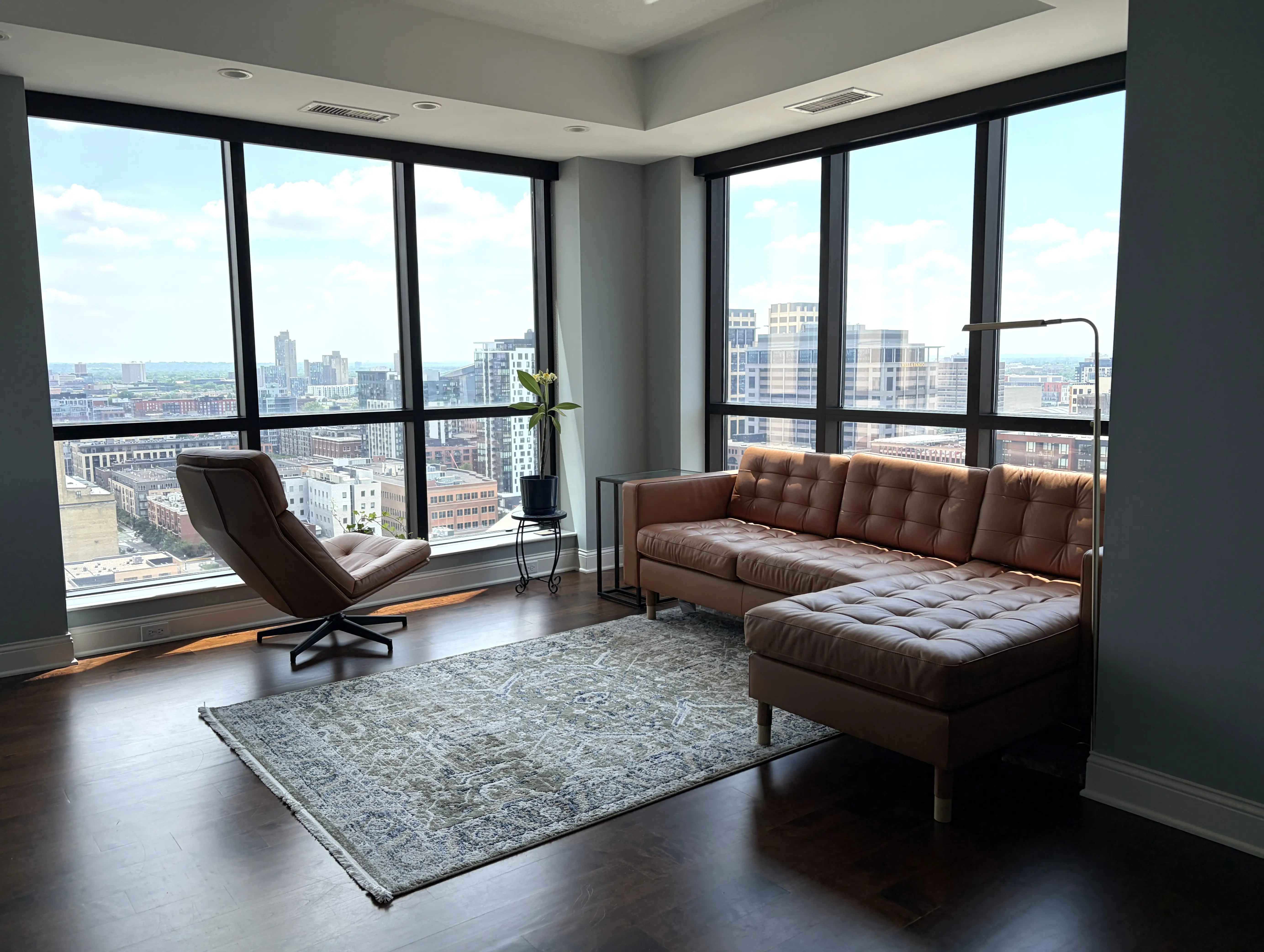 Living room in condo with floor-to-ceiling windows, leather couch