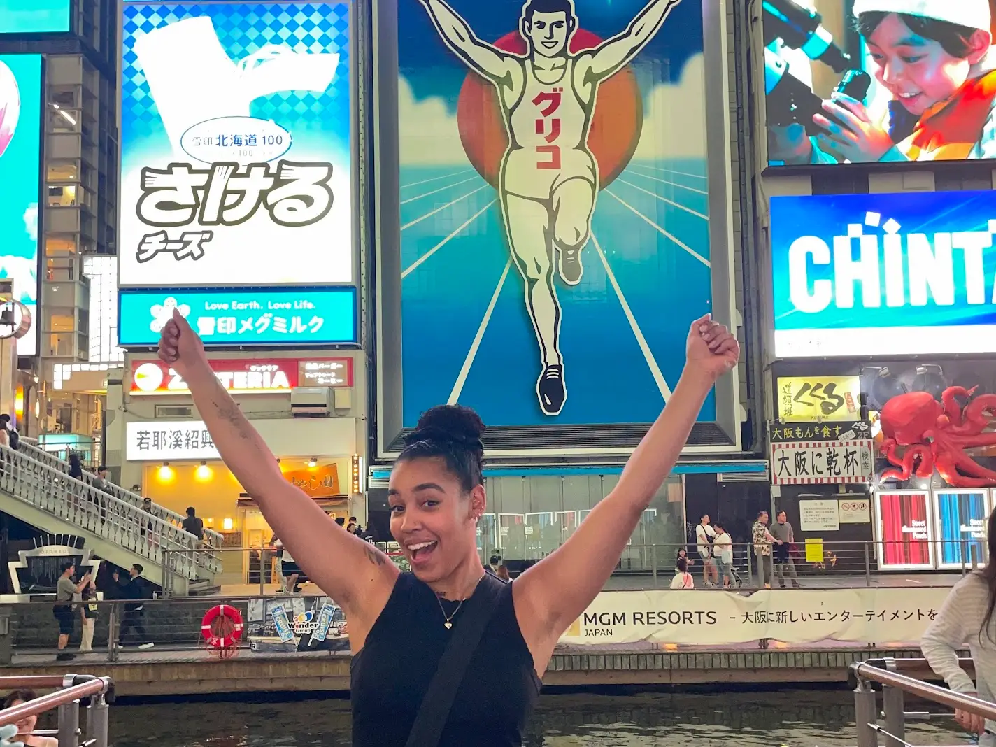 Woman smiling with arms up in front of poster in store