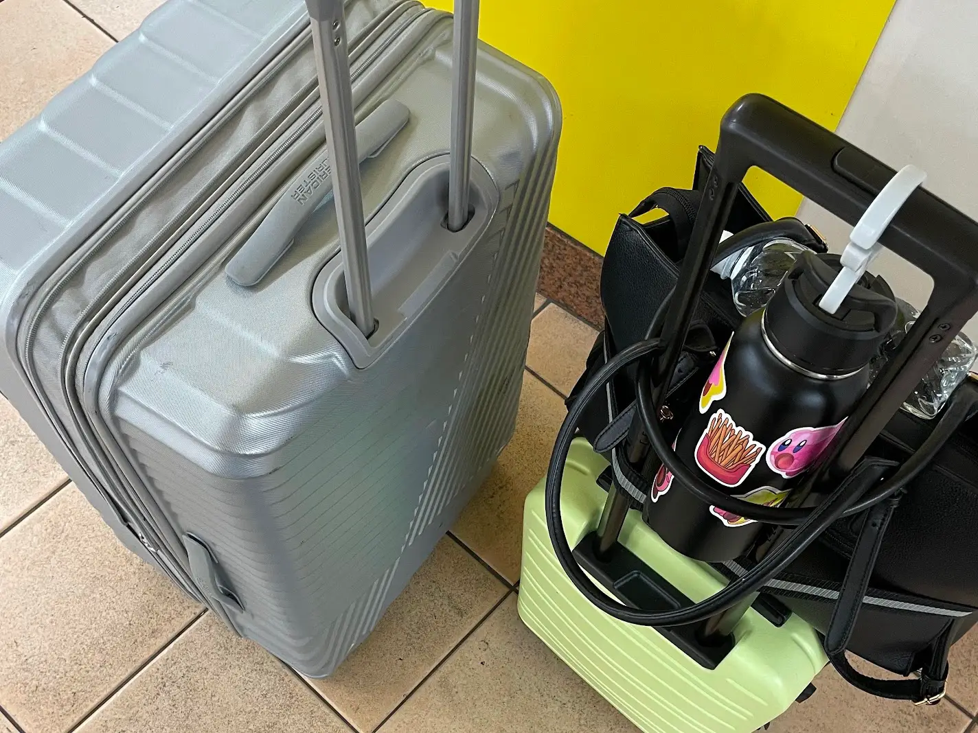 Suitcase and carry-on bag with water bottle, purse on top