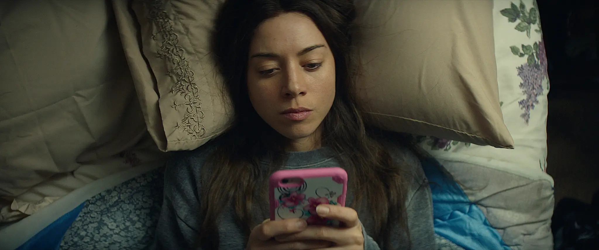 Aubrey Plaza laying down looking at her phone
