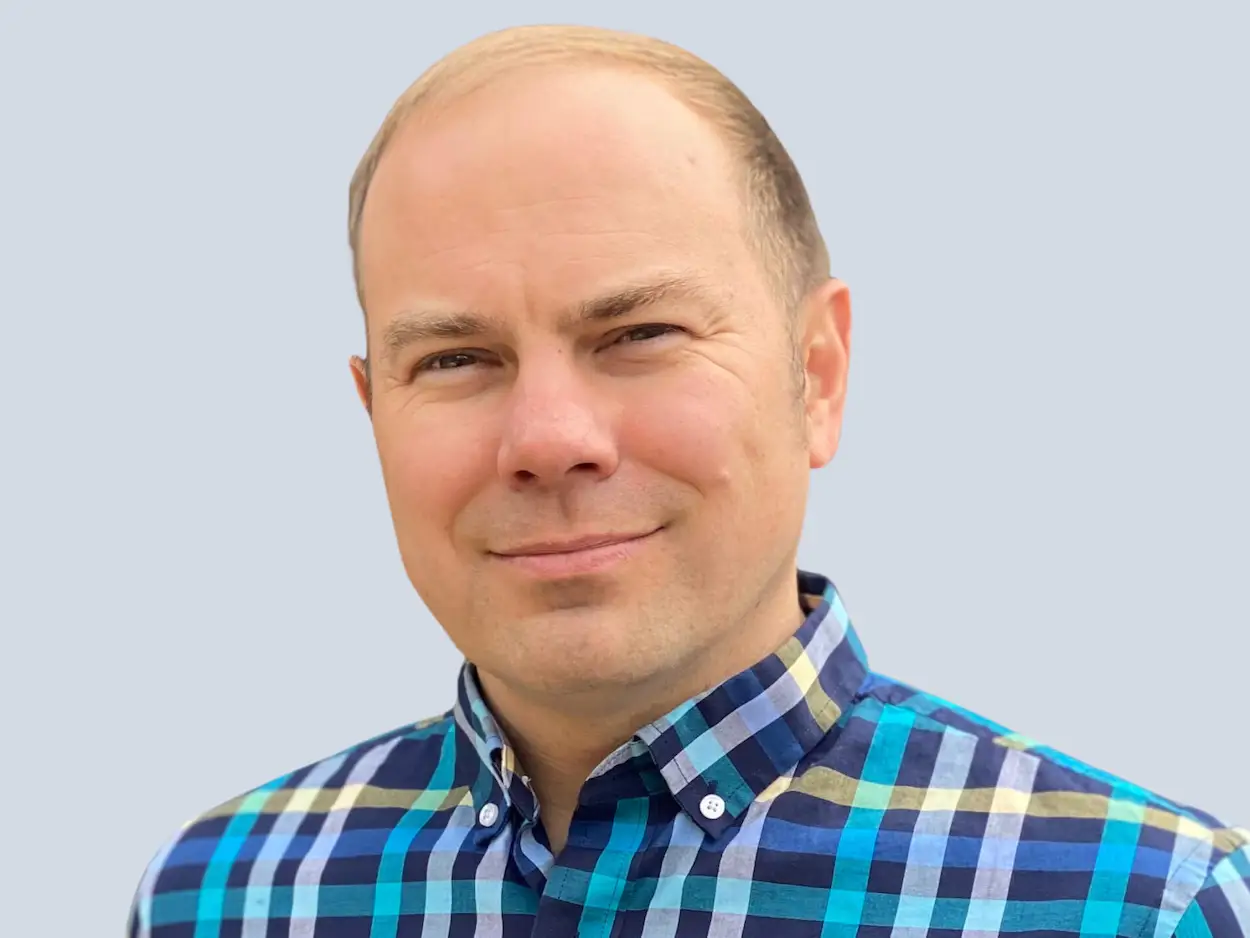 Modular cofounder and CEO Christ Lattner, in front of a gray background and wearing a blue-checked shirt.