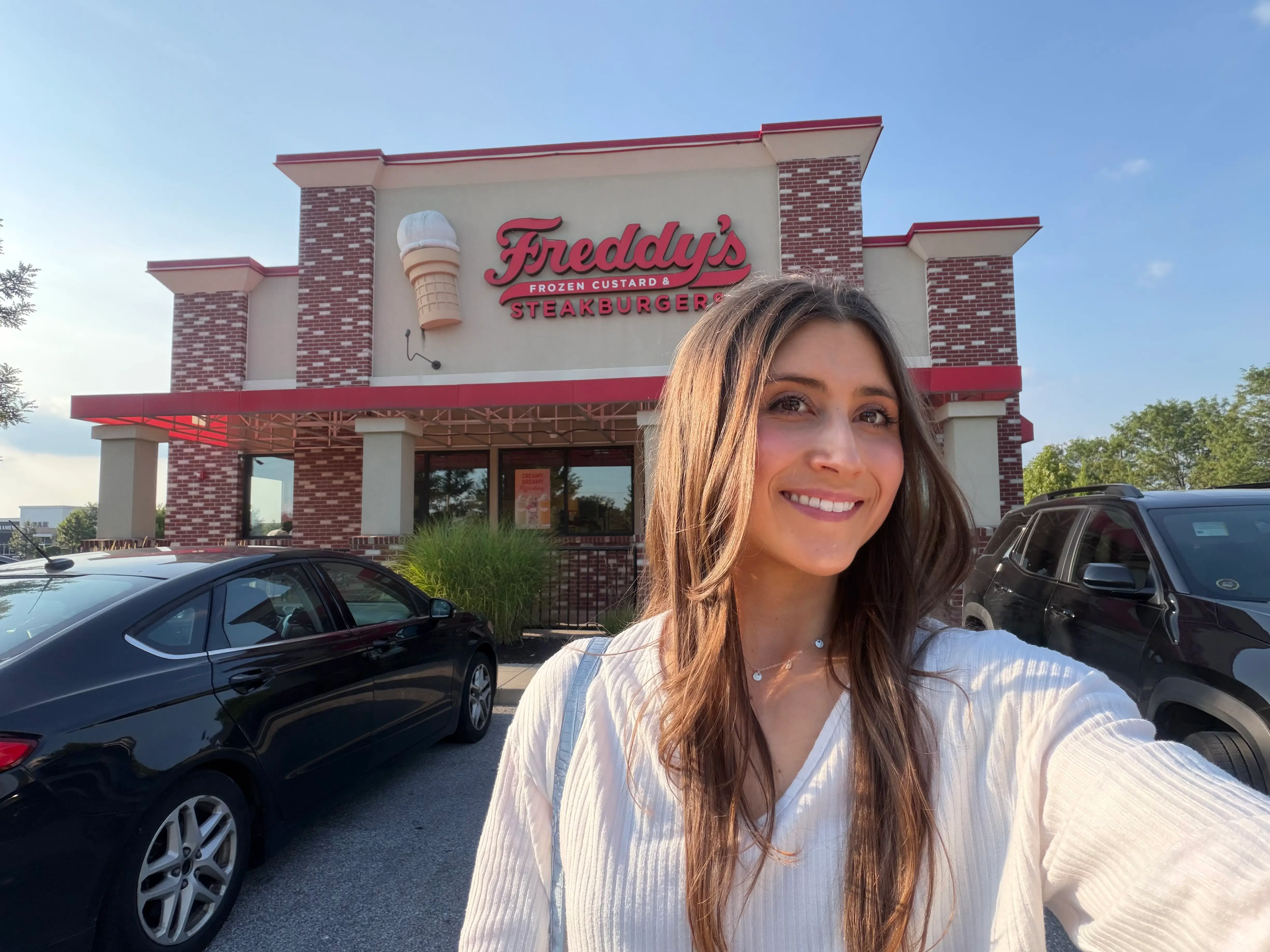 Woman smiling in front of Freddy's Frozen Custard and Steakburgers