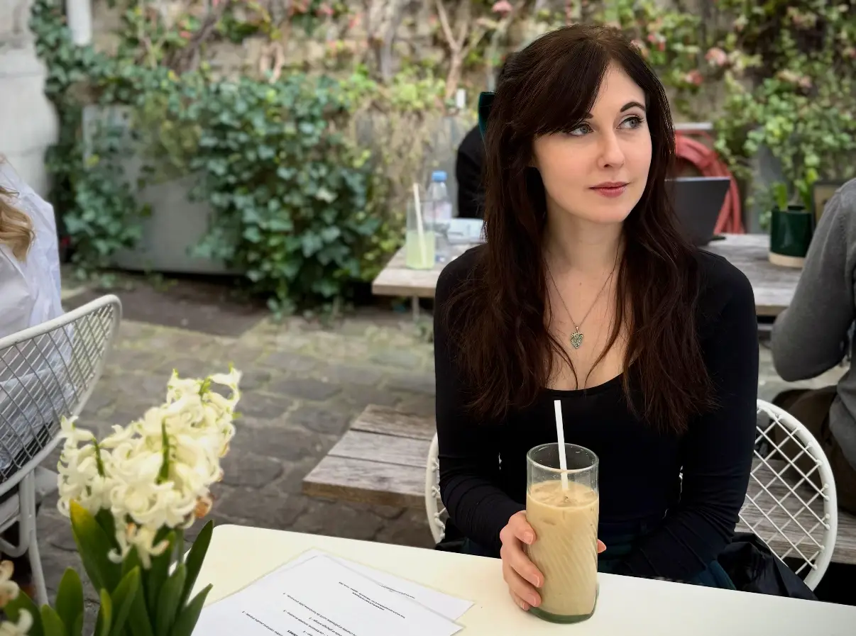 Woman smiling in outdoor cafe with an iced drink
