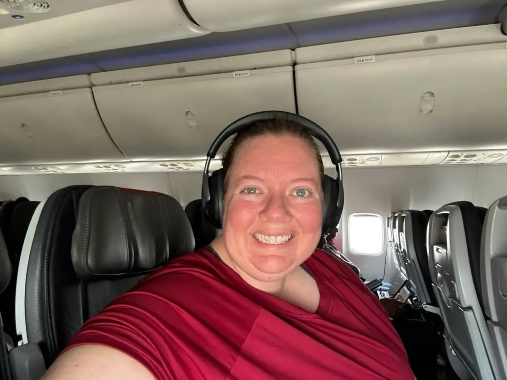 A woman wearing headphones is sitting in an airplane.
